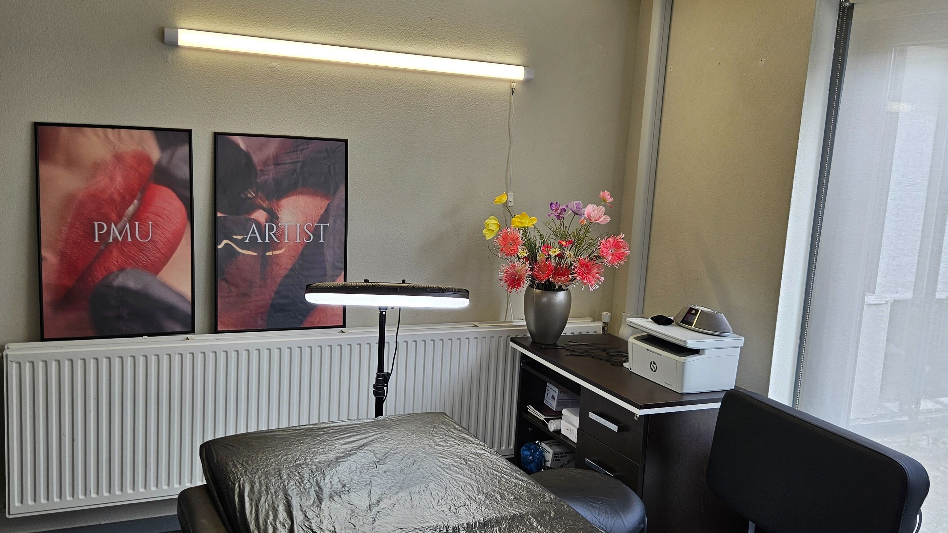 Interieur van Pmu- Tattoo by Mila in Ridderkerk, Zuid-holland, NL met bloemen en posters aan de muur.