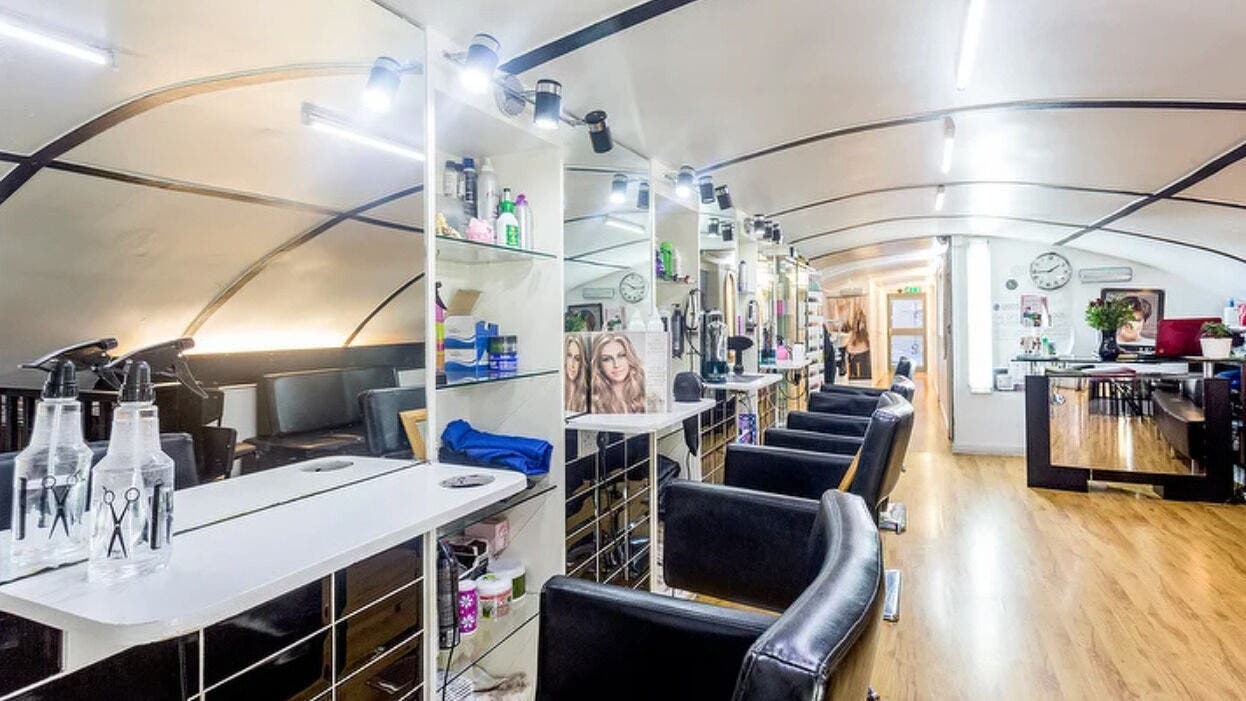 Modern interior of Amandas Hair, Beauty & Aesthetics Salon, London, England, GB. Sleek chairs and styling stations visible.