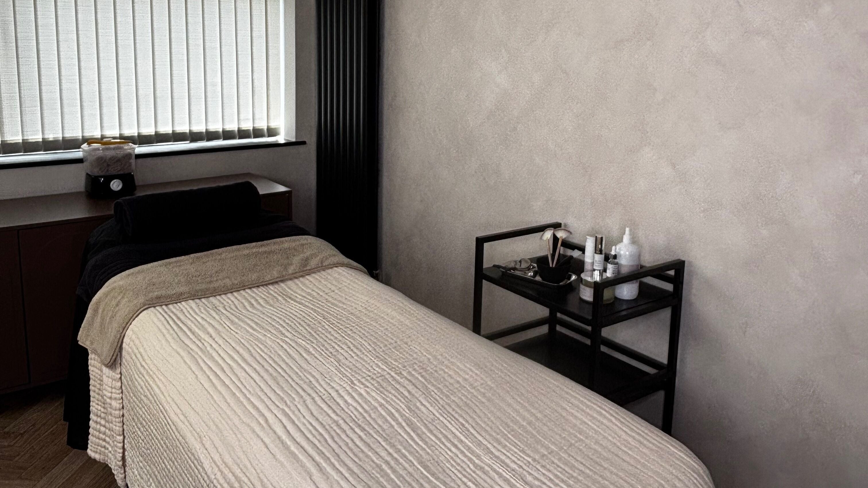 Calming treatment room at HR Skin Collective, Northwich, England, GB with a massage bed and skincare essentials.