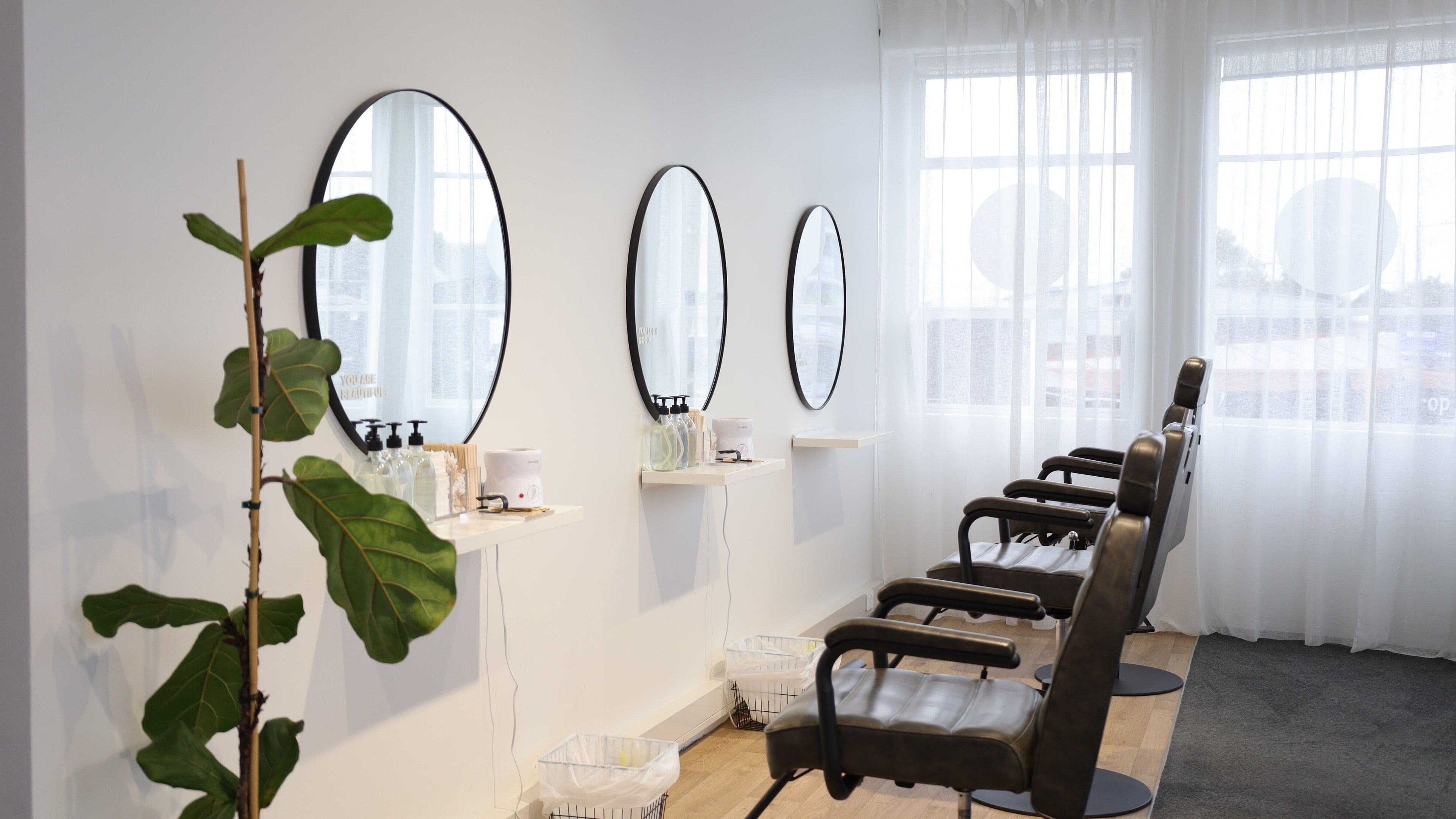 Elegant salon chairs and mirrors at Nude & Co in Auckland, NZ, offering a serene beauty experience.