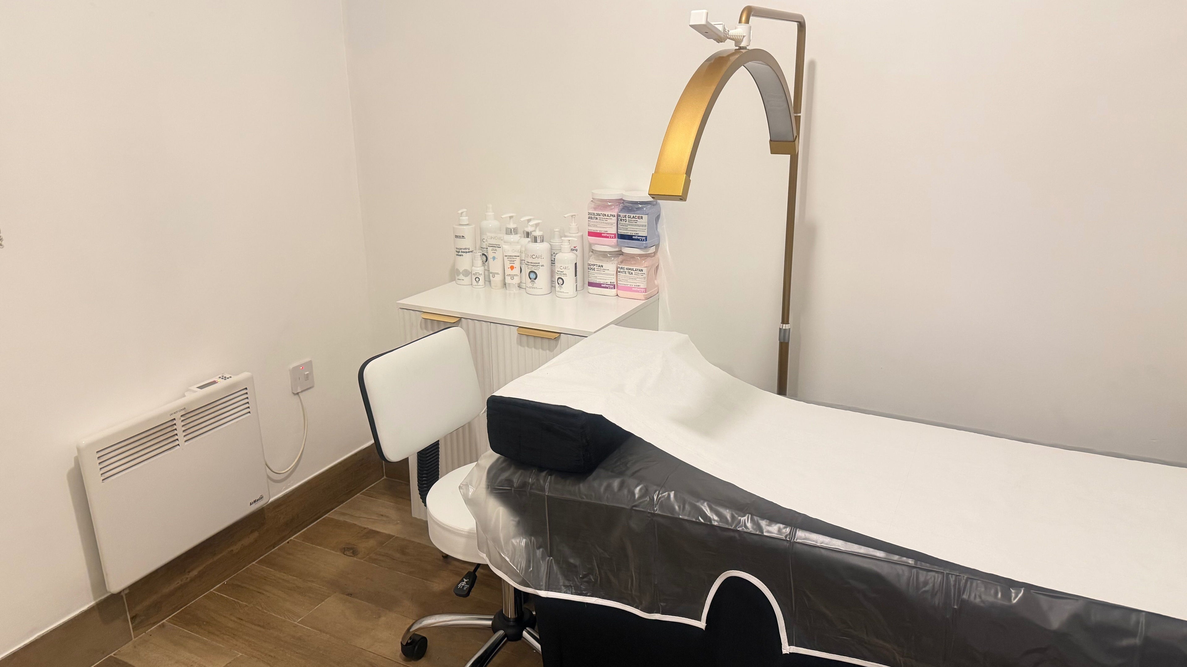 Elegant treatment room at Skin By Ferda, London, England, GB, featuring a massage bed and skincare products.