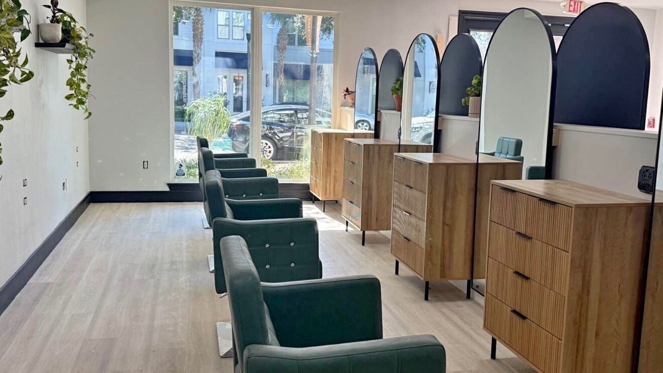 Elegant salon interior at Ateliê Coiffeur, Windermere, Florida, US with chic green chairs and wooden dressers.