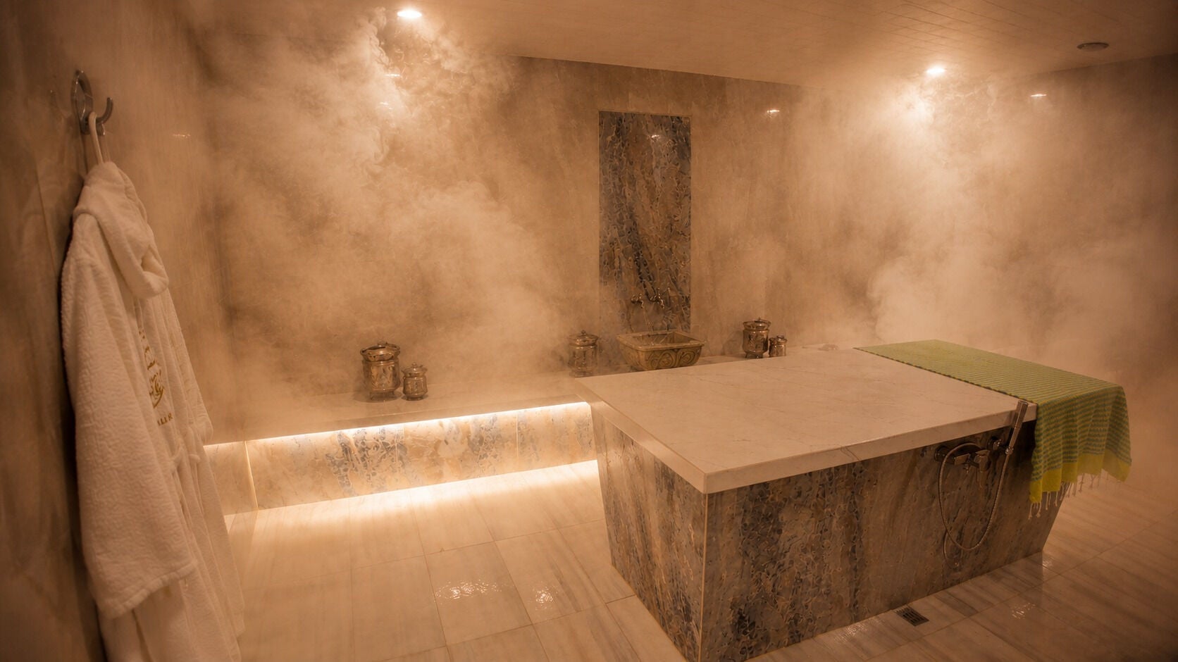 Luxurious steam room at Taj Spa By Samar, Roswell, Georgia, US, with a serene marble table and elegant robe.