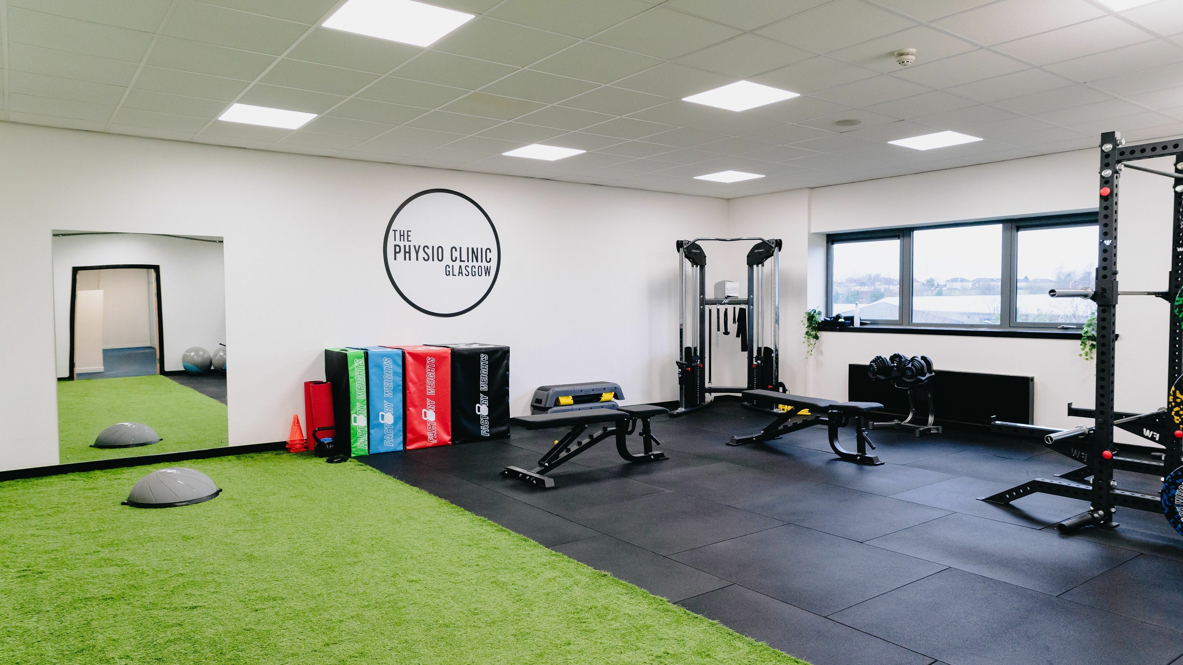 Modern gym interior at The Physio Clinic Glasgow in Glasgow, Scotland, GB with equipment and green flooring.