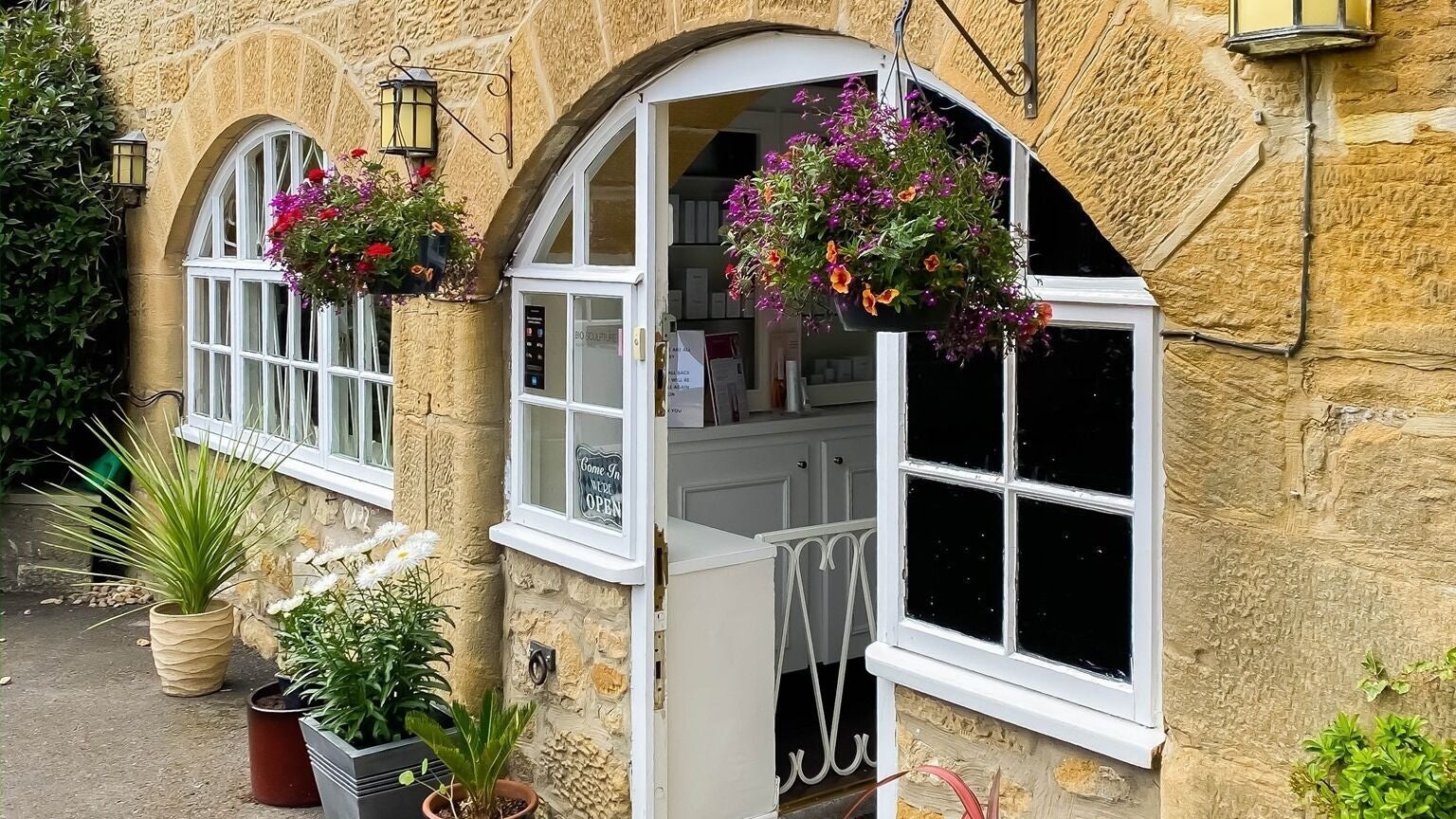 Entrance of Ultimate Skin Clinic, Seaton Burn, England, GB, with stone walls and flowering plants.