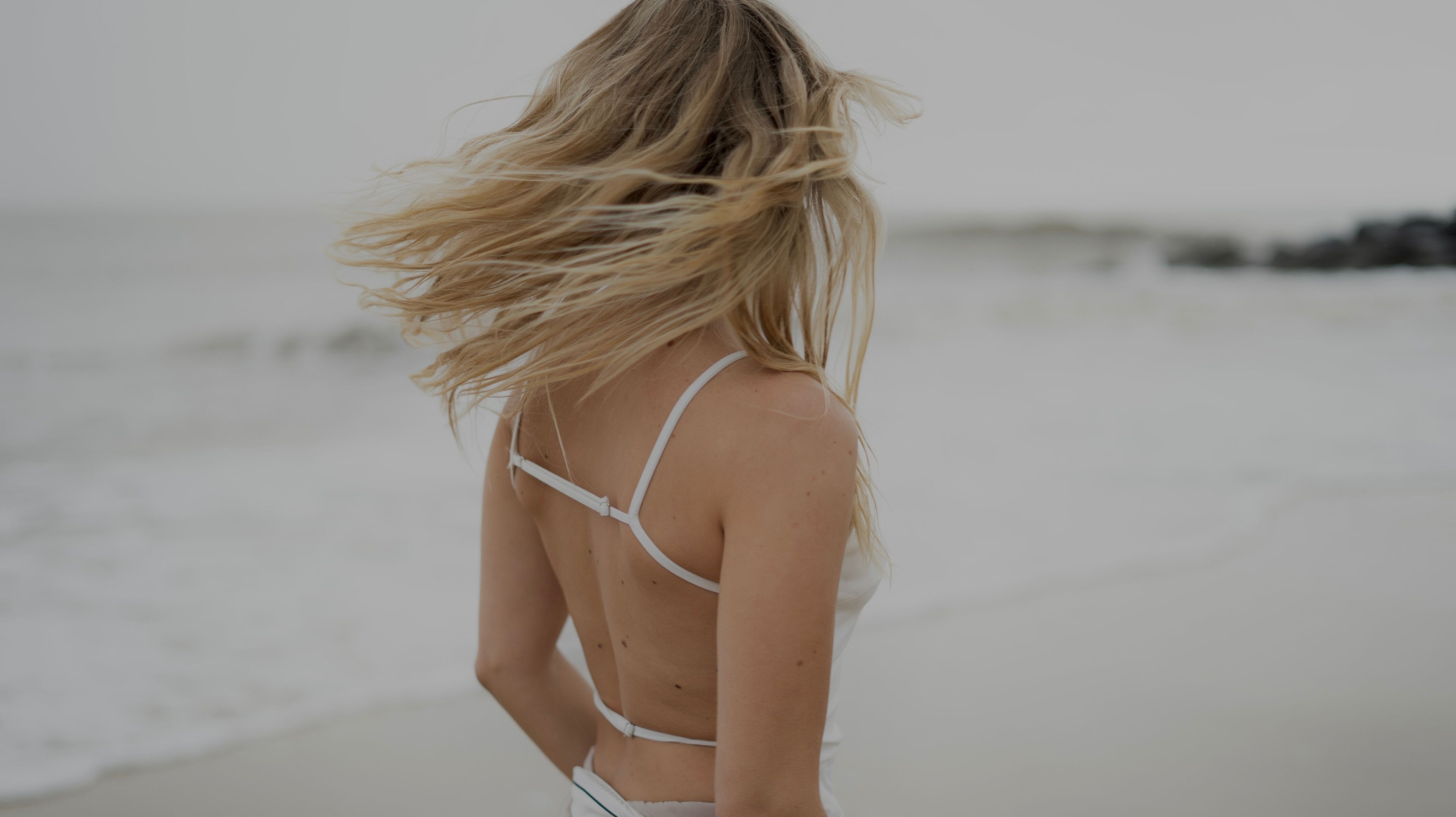 Woman with flowing hair on a serene beach near V O S, Beccles, England, GB.