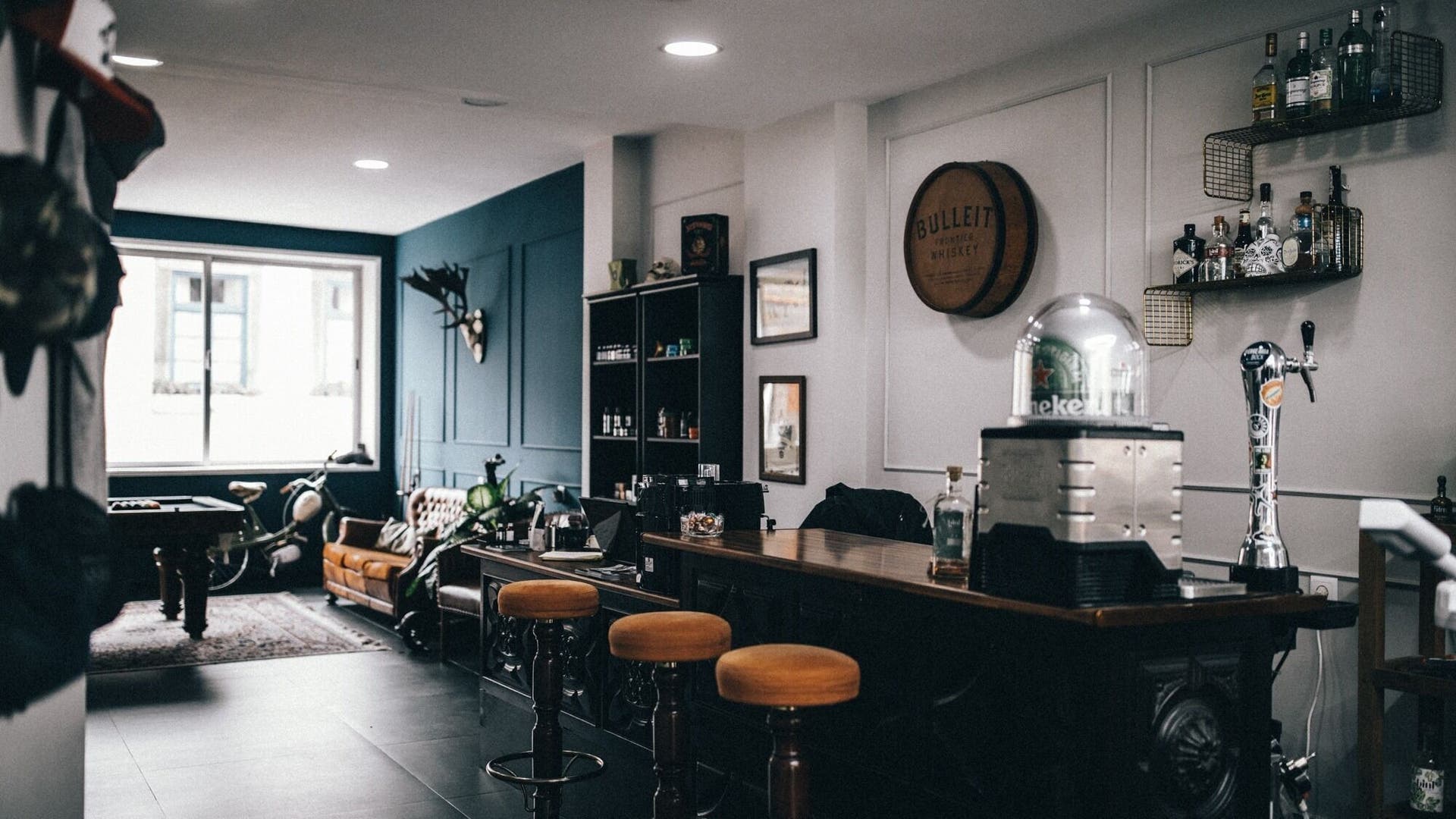 Cozy interior of Barbershop Men's Cave by Le Beard, Porto, PT, featuring bar stools and whiskey decor.