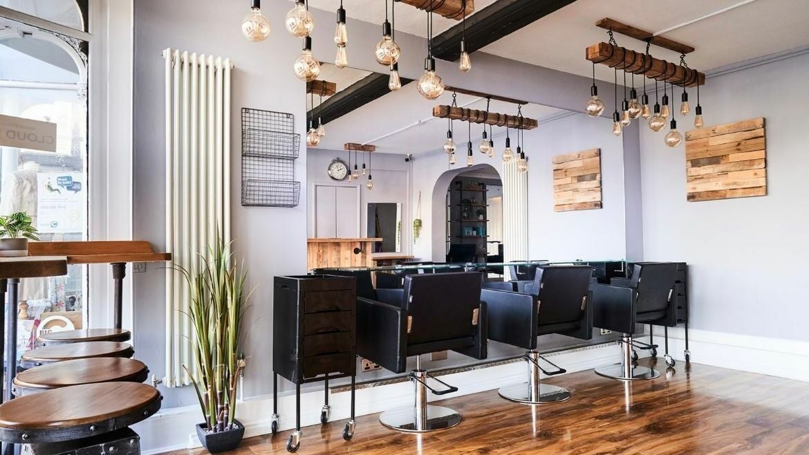 Modern salon interior at The Ultimate Touch in Wymondham, England, GB, featuring sleek chairs and rustic decor.