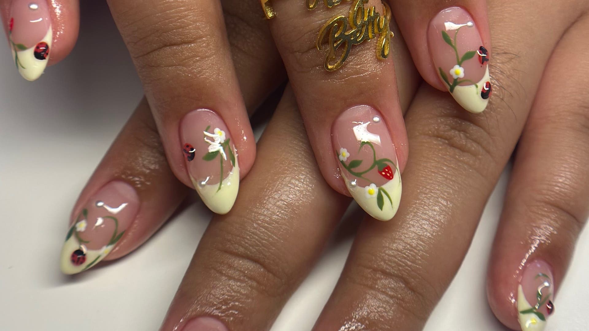 Floral nail art design at Pettynailsbybetty, Central Islip, New York, US showcasing intricate flowers and ladybugs.