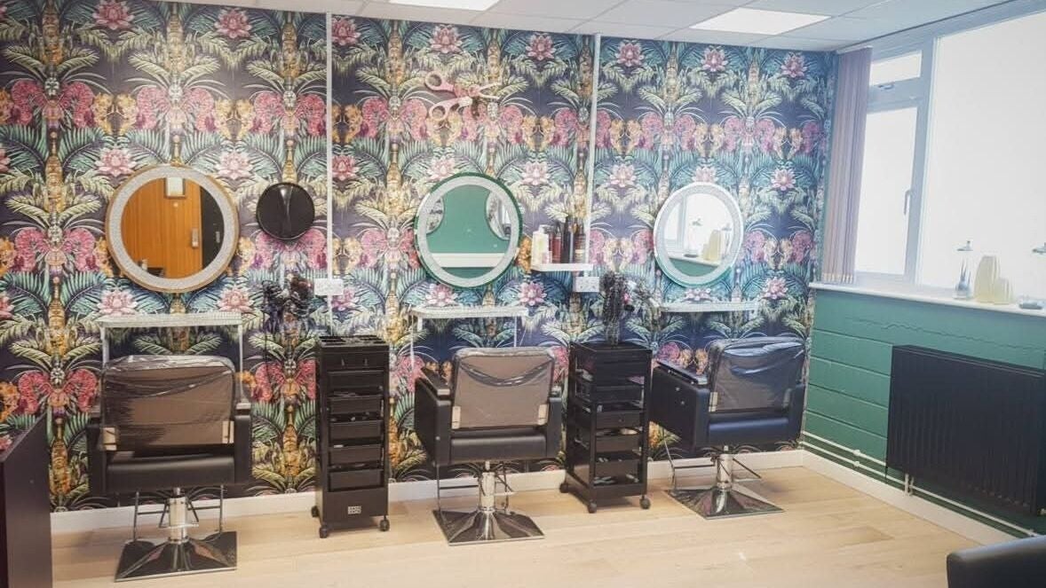 Amore salon interior in St Austell, England, GB with vibrant floral wallpaper and modern styling chairs.