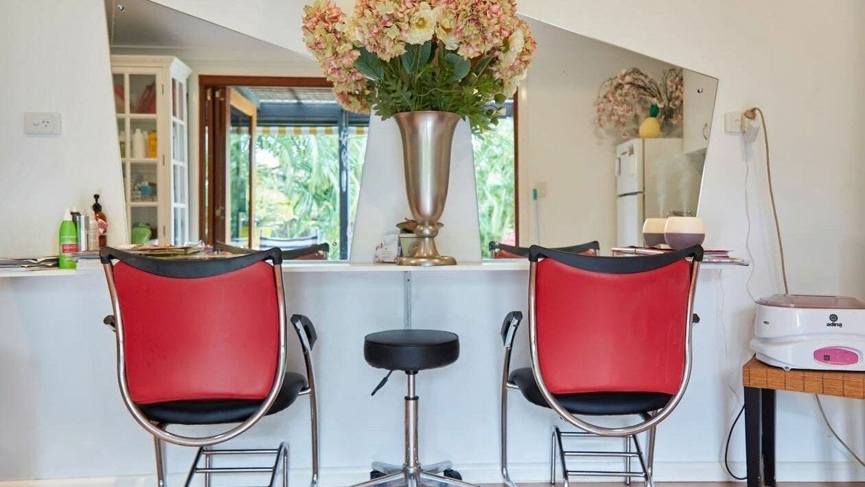 Elegant interior of My Wife's Folly Hairdressing in Clayfield, Queensland, AU with red chairs and floral decor.