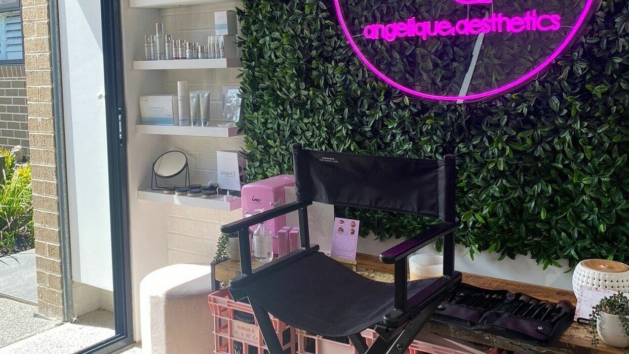 Angelique Aesthetics lounge featuring a neon sign, makeup chair, and product shelf in Melbourne, Victoria, AU.