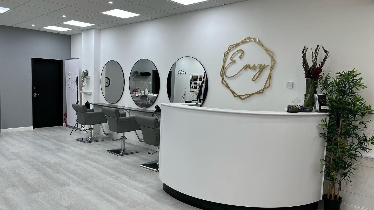 Modern interior of Envy Hair & Extensions salon in Eastbourne, England, GB with chic decor and styling chairs.