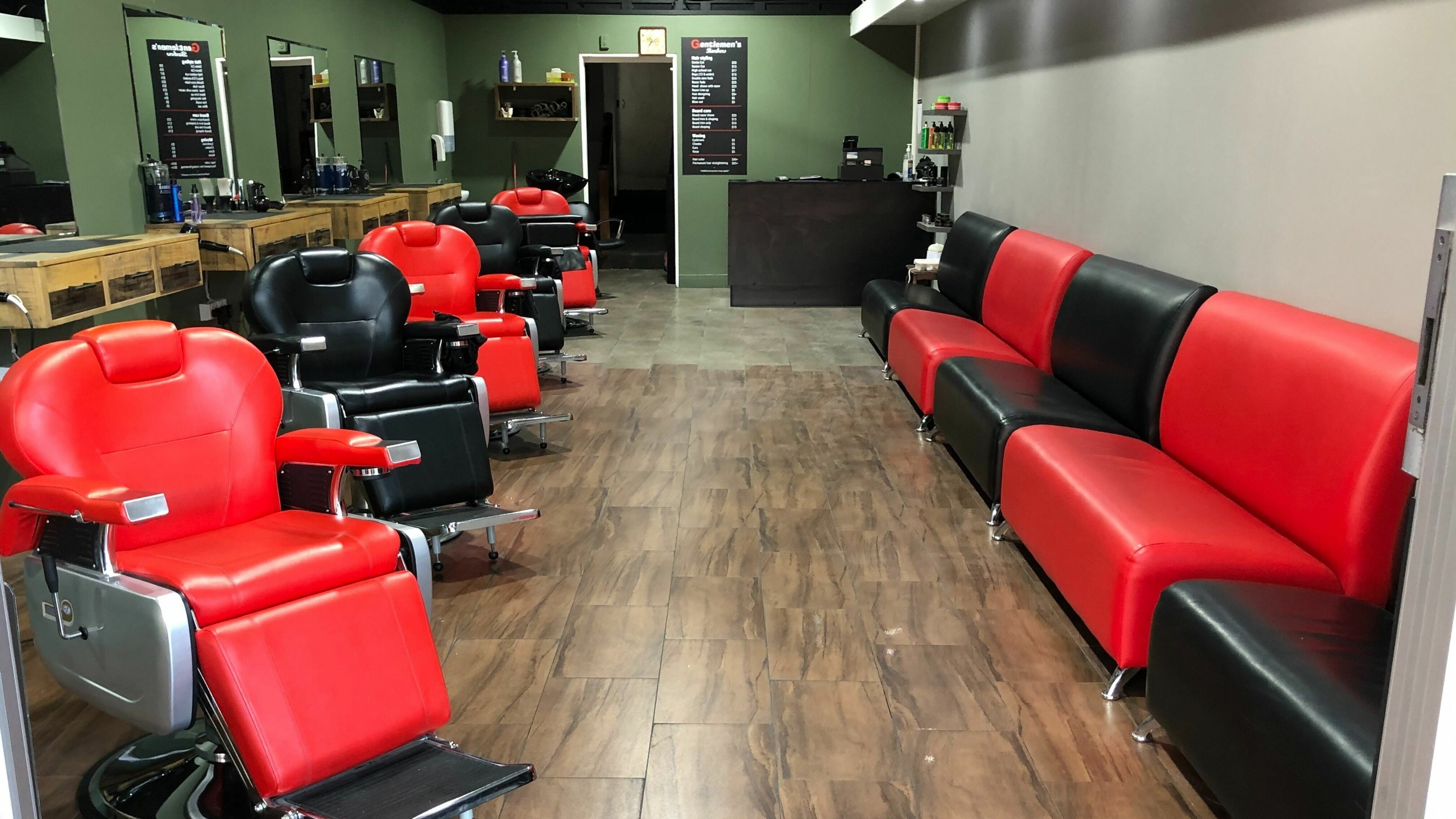 Interior of Gentlemen's Barbers Onehunga in Auckland, NZ, featuring red and black barber chairs and sofas.