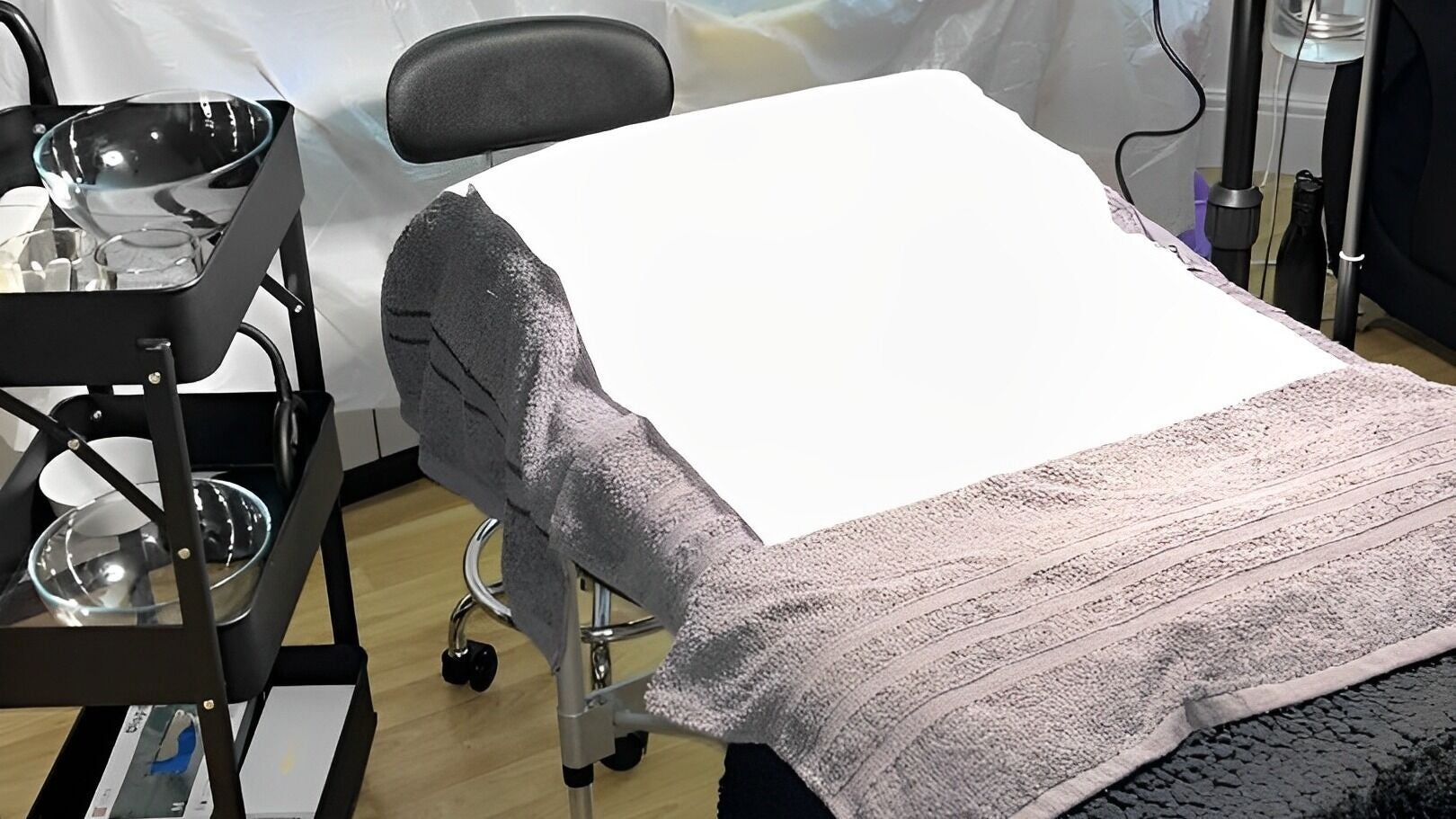 Cozy treatment bed at Sculpt & Glow Studio, London, England, GB, with soft grey linens and tranquil atmosphere.