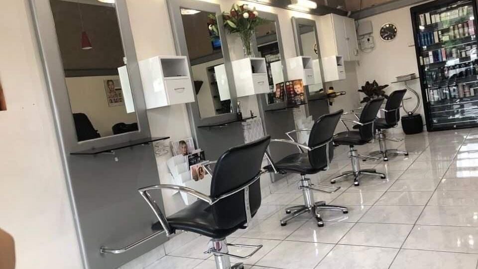 Modern salon interior at Caprice Hair & Beauty, Melbourne, Victoria, AU with stylish black chairs and mirrors.