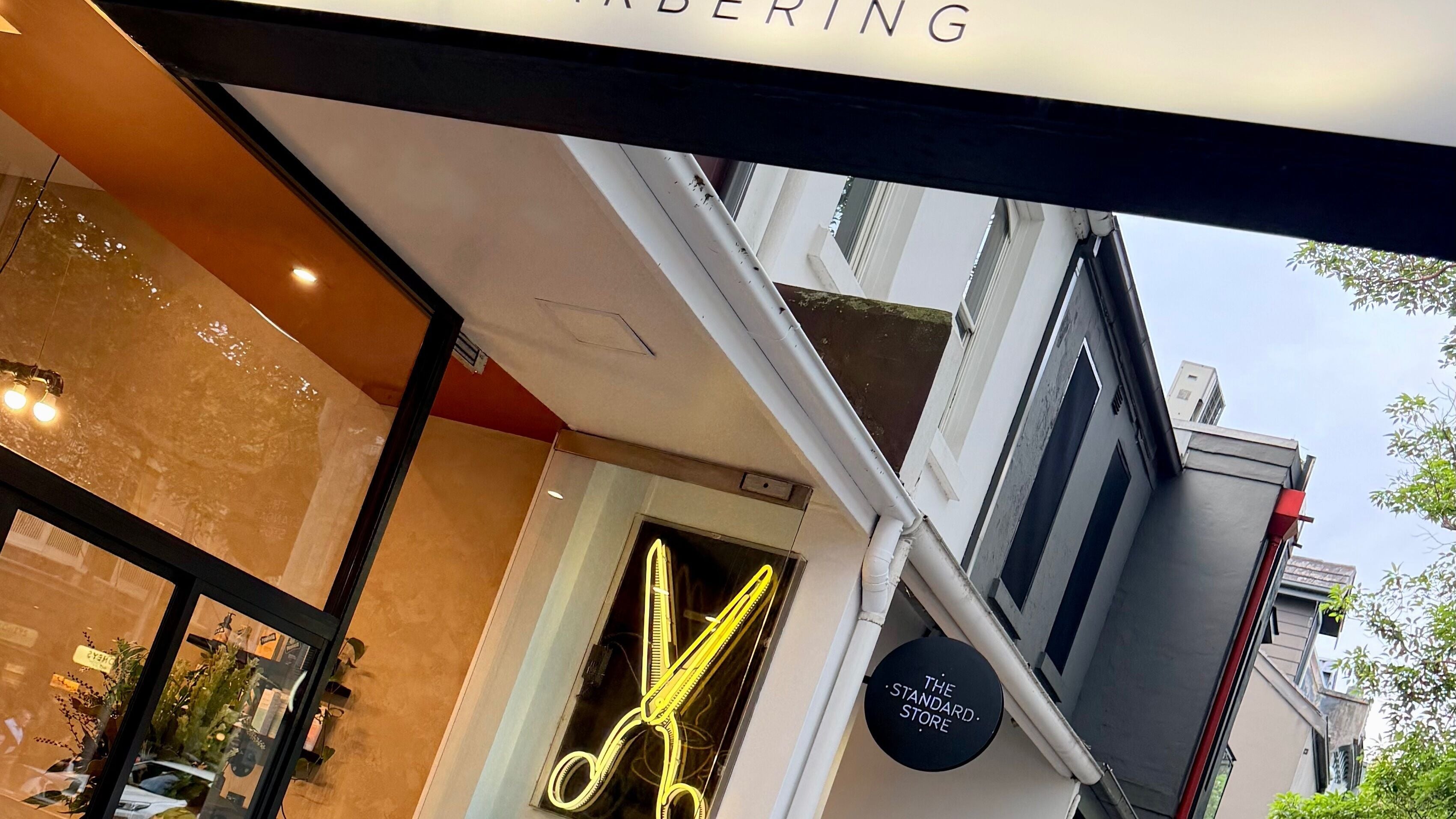 Exterior of Verve Barbering - Surry Hills with neon scissors sign in Surry Hills, New South Wales, AU.
