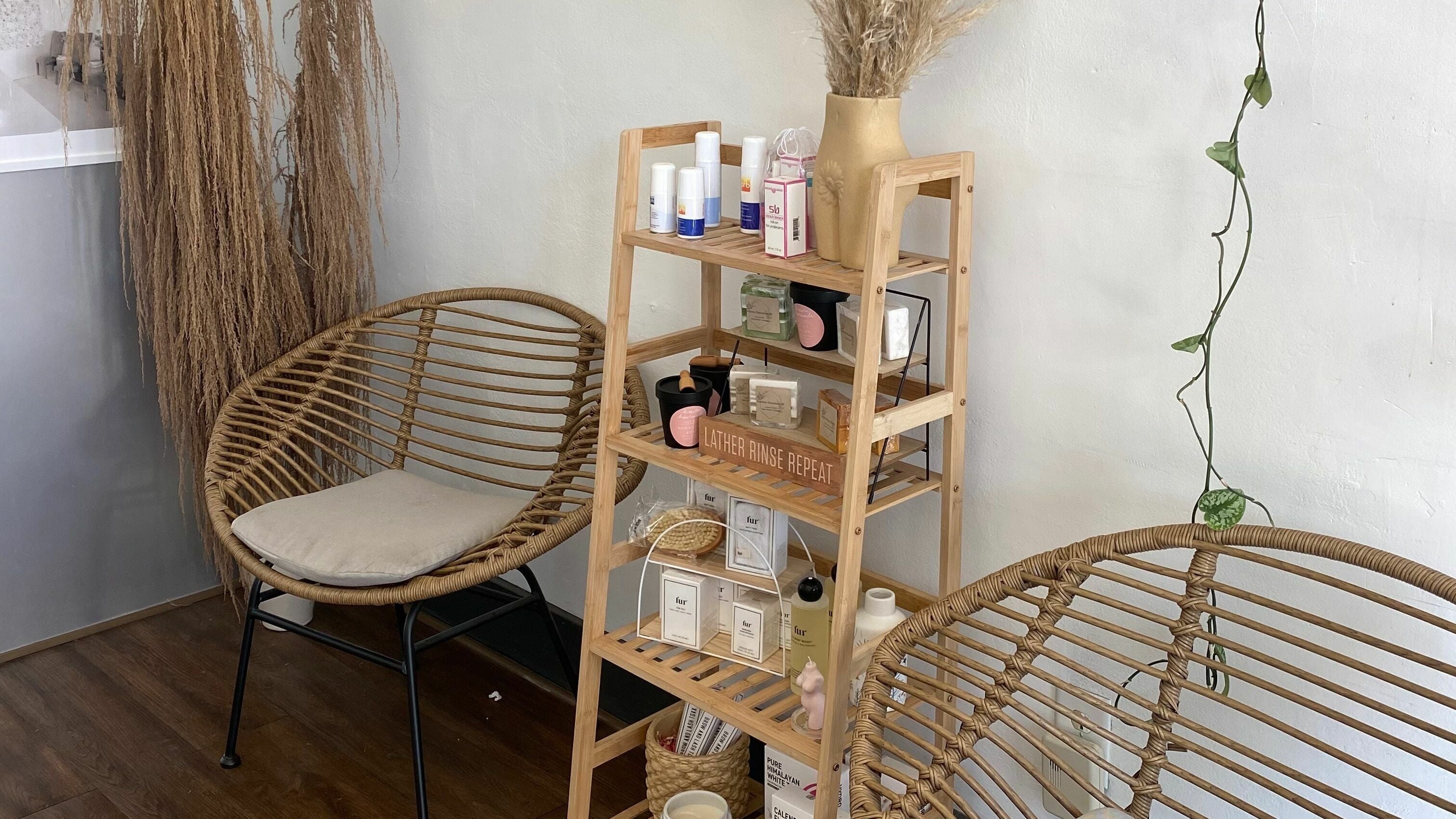 Relaxing corner at Daisy's House of Beauty, Long Beach, California US, featuring wicker chairs and a display shelf.