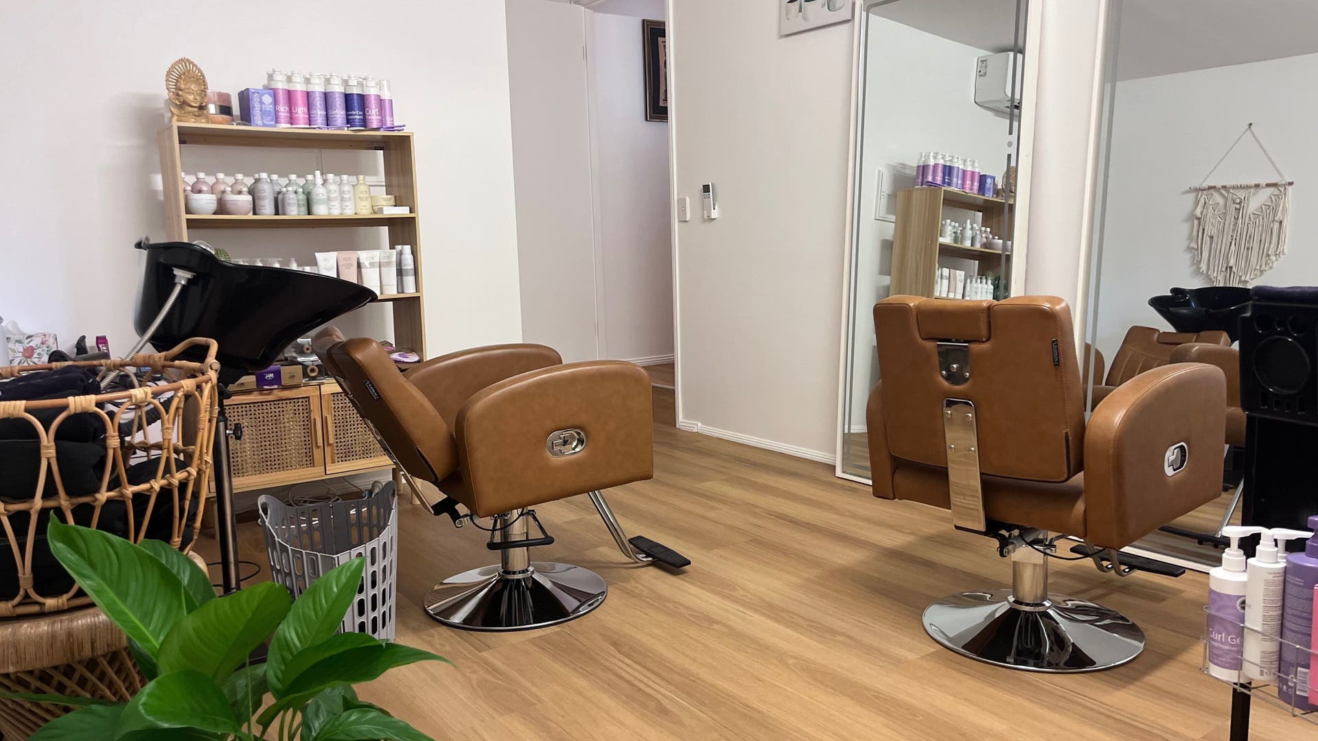 Interior of Curly & Blonde salon in Bardon, Queensland, AU featuring salon chairs and hair products on display.