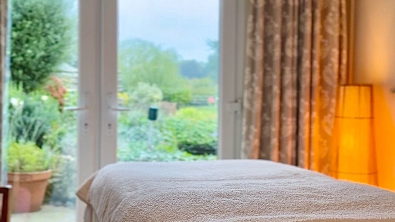Relaxing treatment room at Apollonia Beauty in Kennington, England with garden view and soft lighting.