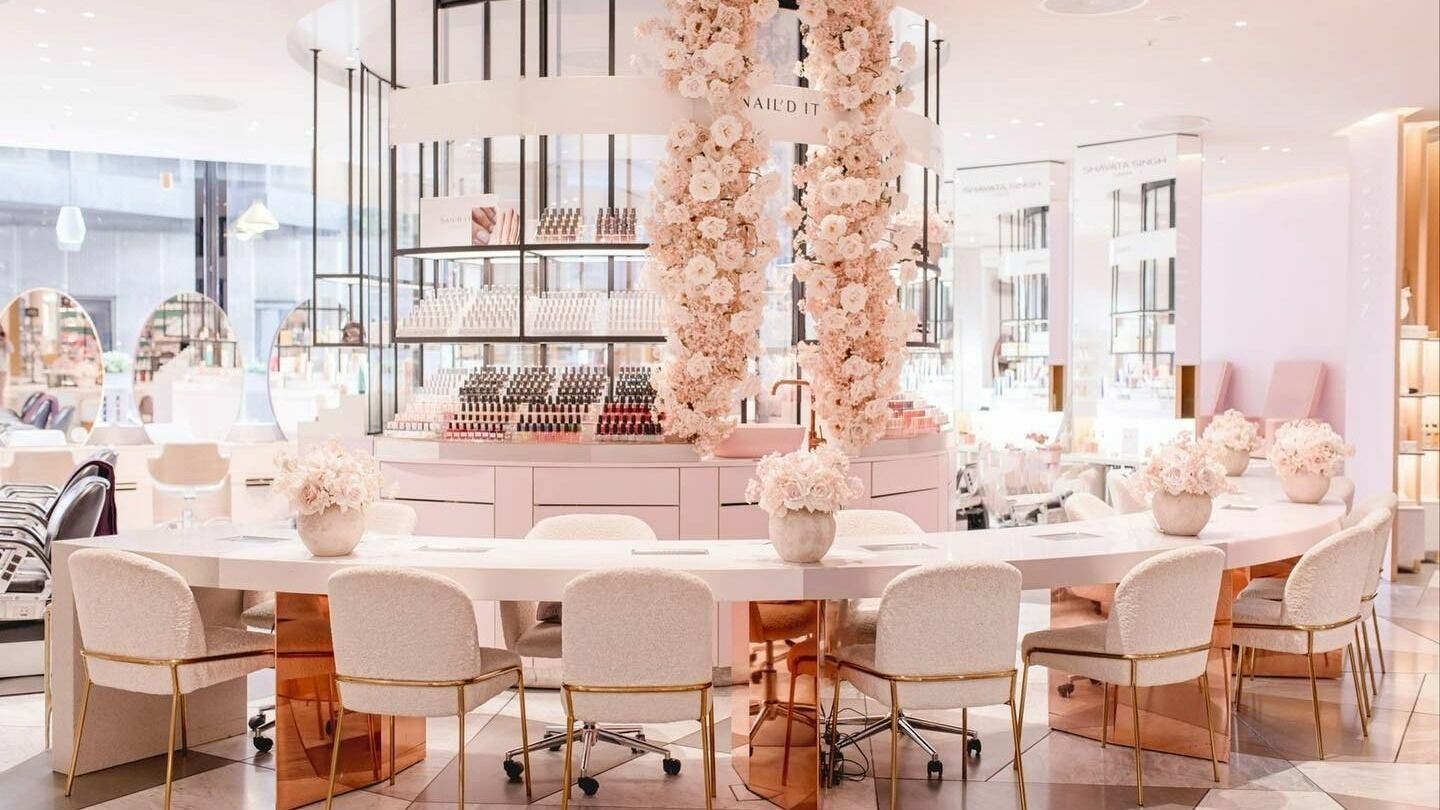 Elegant interior of Nail'd It Battersea in London, England, GB, showcasing chic nail stations and floral decor.