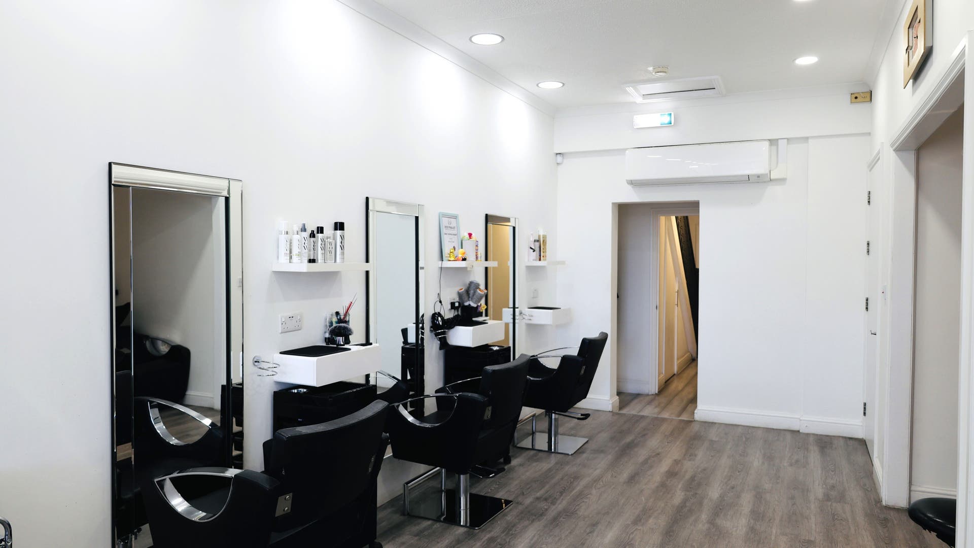 Modern hair salon interior at Sunrayz Hair & Beauty in Hornchurch, England, GB with sleek styling chairs and mirrors.