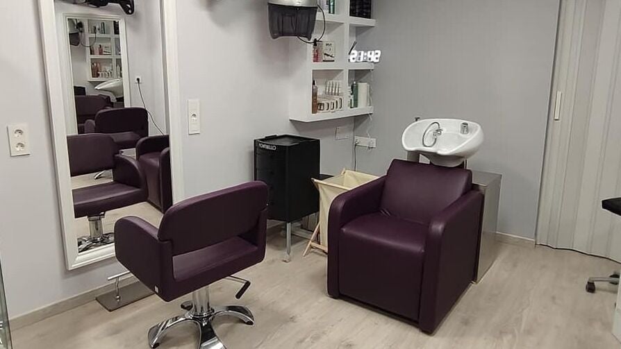 Interior del salón La Paixarela en Zaragoza, Aragón, ES con sillas moradas y lavacabezas moderno.
