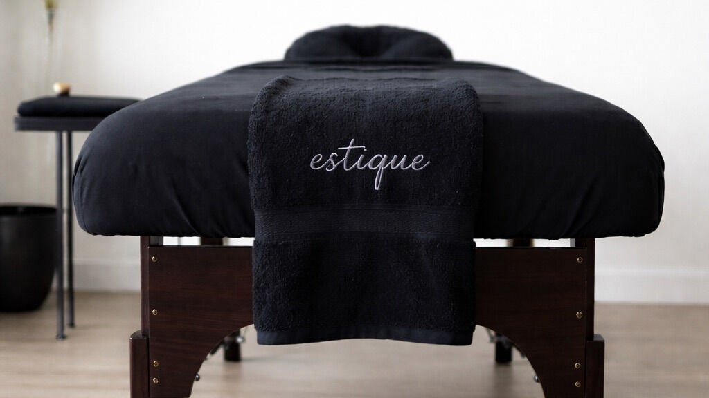 Luxurious spa table at Estique with plush black linens, N/A, N/A, US - perfect for ultimate relaxation.