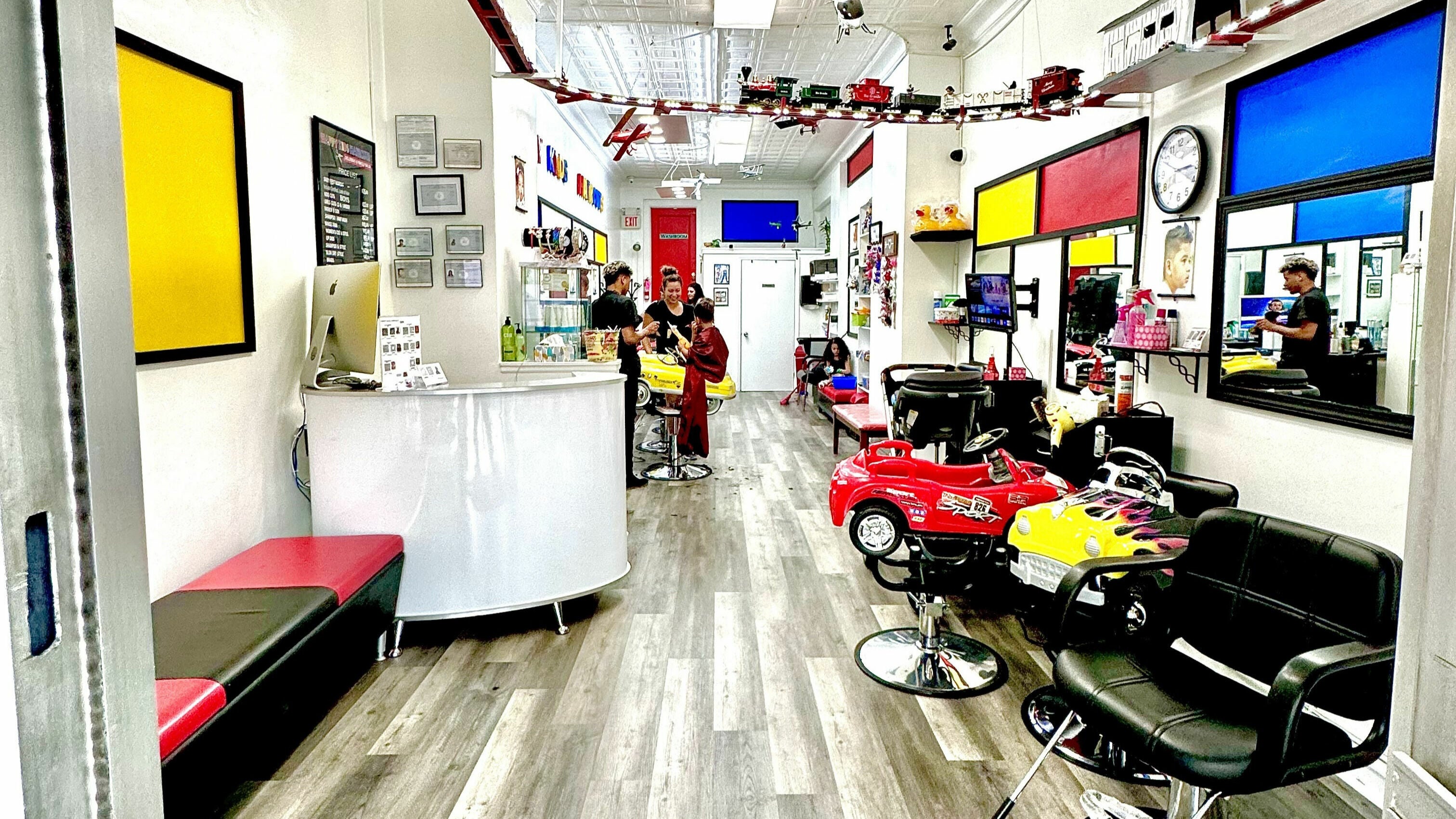 Bright interior of A and G Happy Kids Haircuts in Scarsdale, New York, US with colorful car-style chairs.