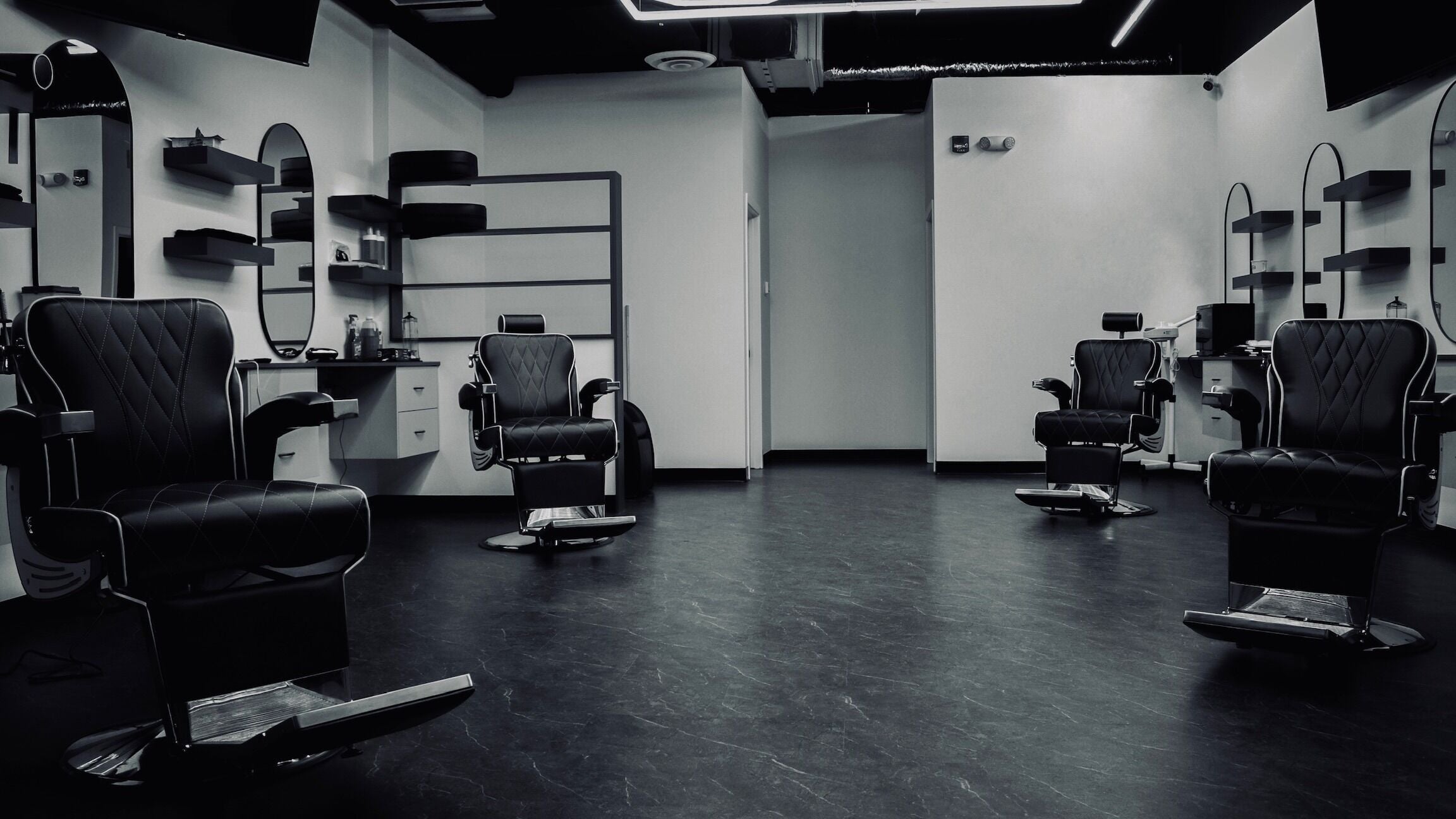 Modern interior of Platinum Barbershop in Edmonton, Alberta, CA, showcasing stylish black chairs and mirrors.