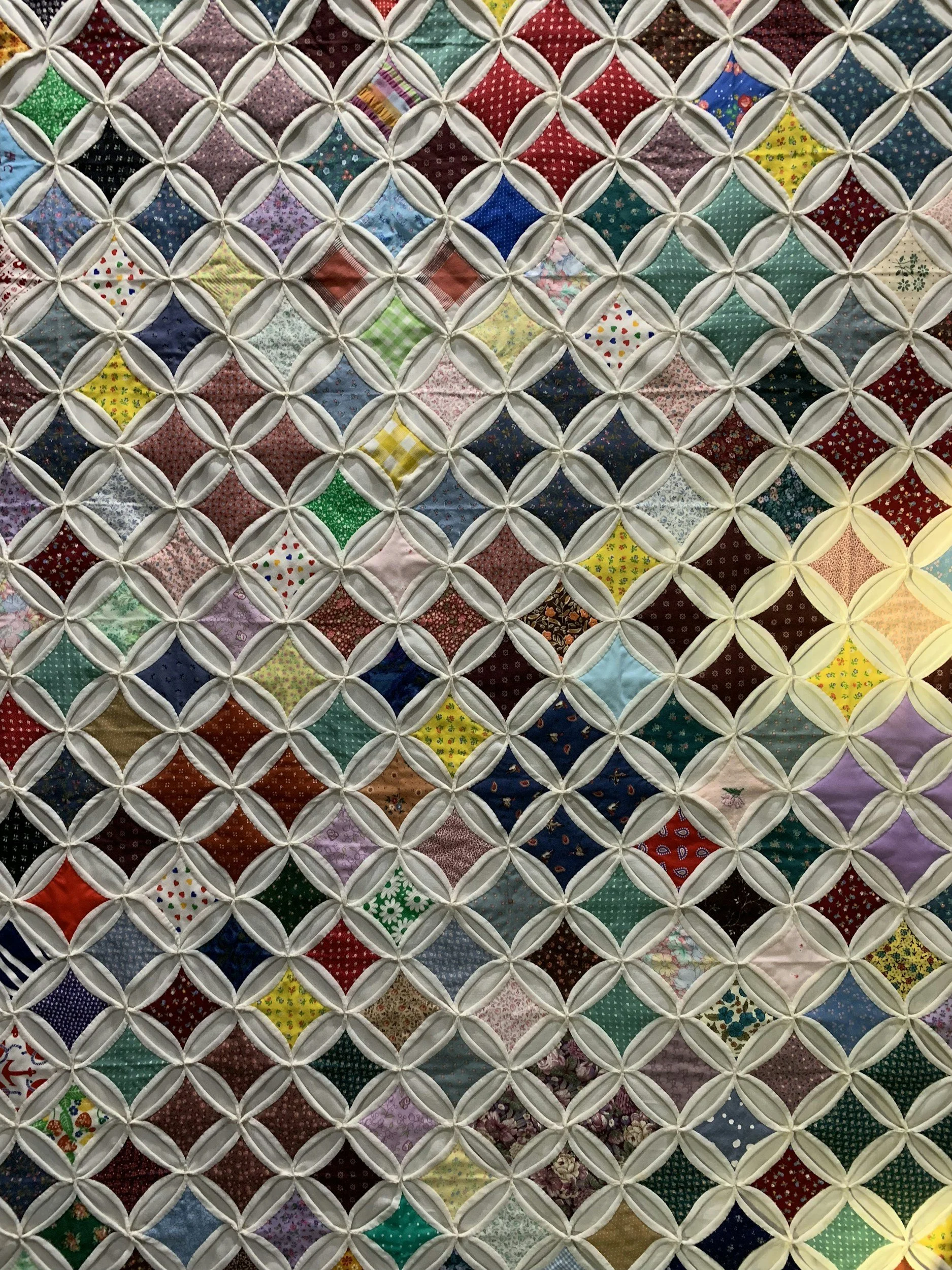 Close-up of a colorful patchwork quilt with a diamond pattern and white borders.