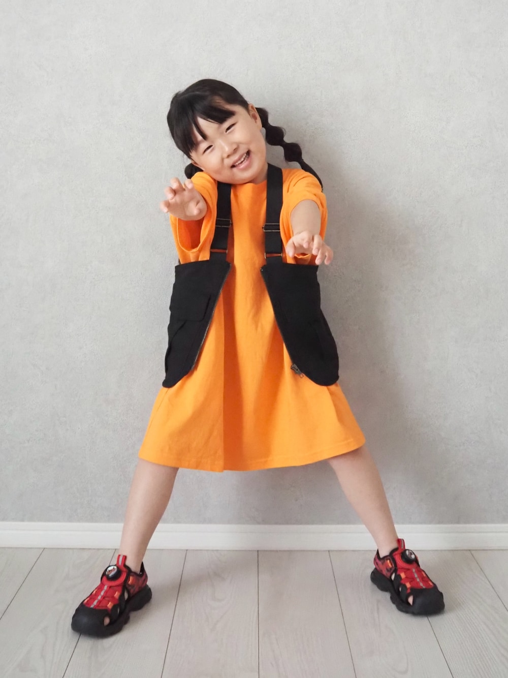 レッド系のサンダル、オレンジ系のワンピースを着用したキッズの夏コーディネートの1枚目の写真