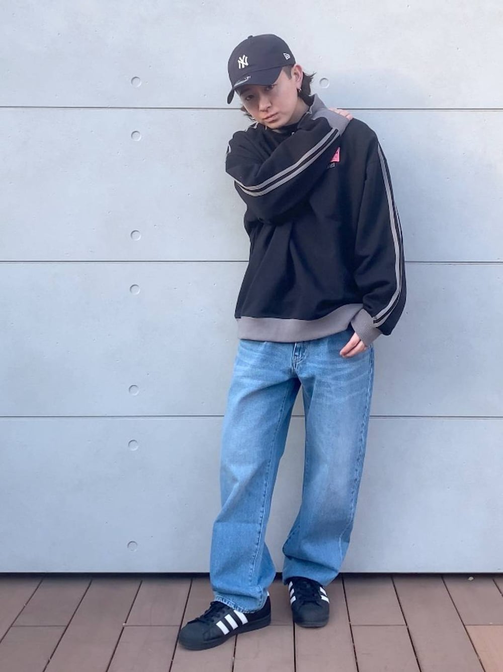 ブルー系のデニムパンツ、ブラック系のスウェット、ブルー系のキャップを着用したメンズの春コーディネートの1枚目の写真