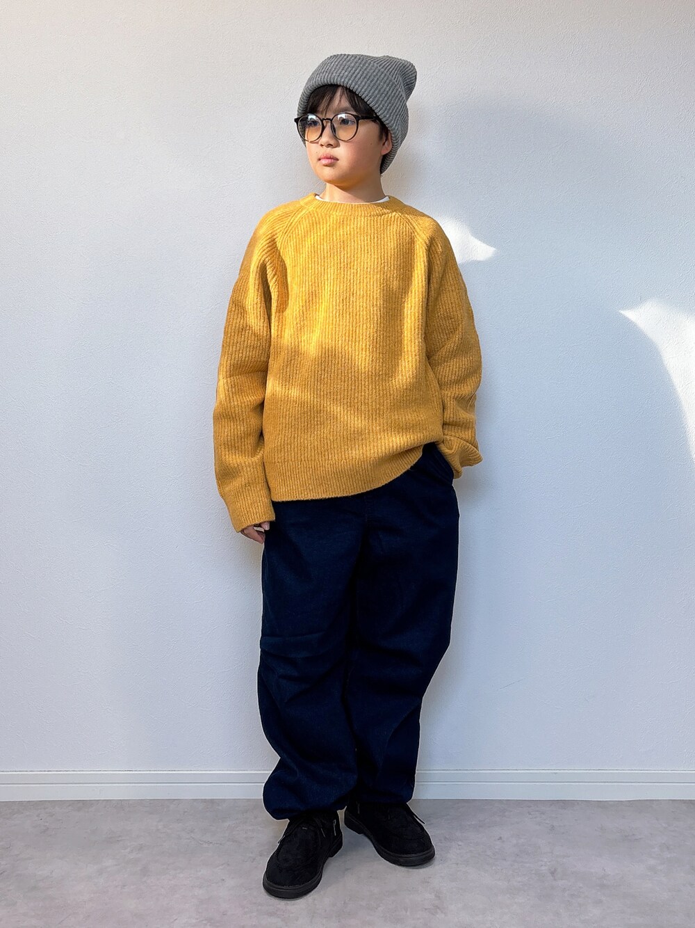 イエロー系のニット/セーター、ブルー系のデニムパンツ、ブラック系のモカシン/デッキシューズを着用したキッズの冬コーディネートの1枚目の写真