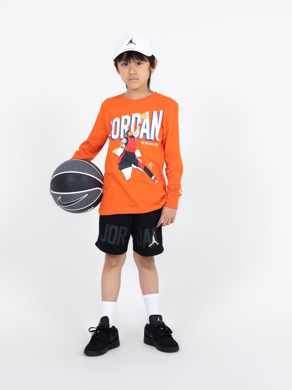 オレンジ系のTシャツ/カットソー、ブラック系のパンツ、ブラック系のスニーカーを着用したキッズの春コーディネートの1枚目の写真