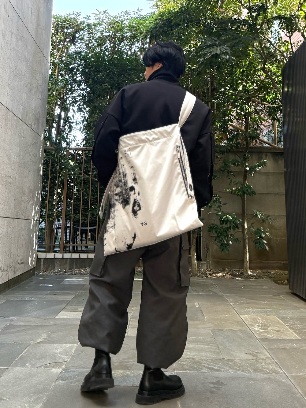 ブラック系のダッフルコート、グレー系のカーゴパンツ、ホワイト系のトートバッグを着用したメンズの春コーディネートの1枚目の写真