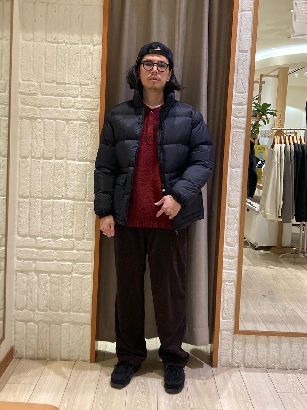 レッド系のニット/セーター、ブラウン系のその他パンツ、ブラック系のダウンジャケット/コートを着用したメンズの冬コーディネートの1枚目の写真