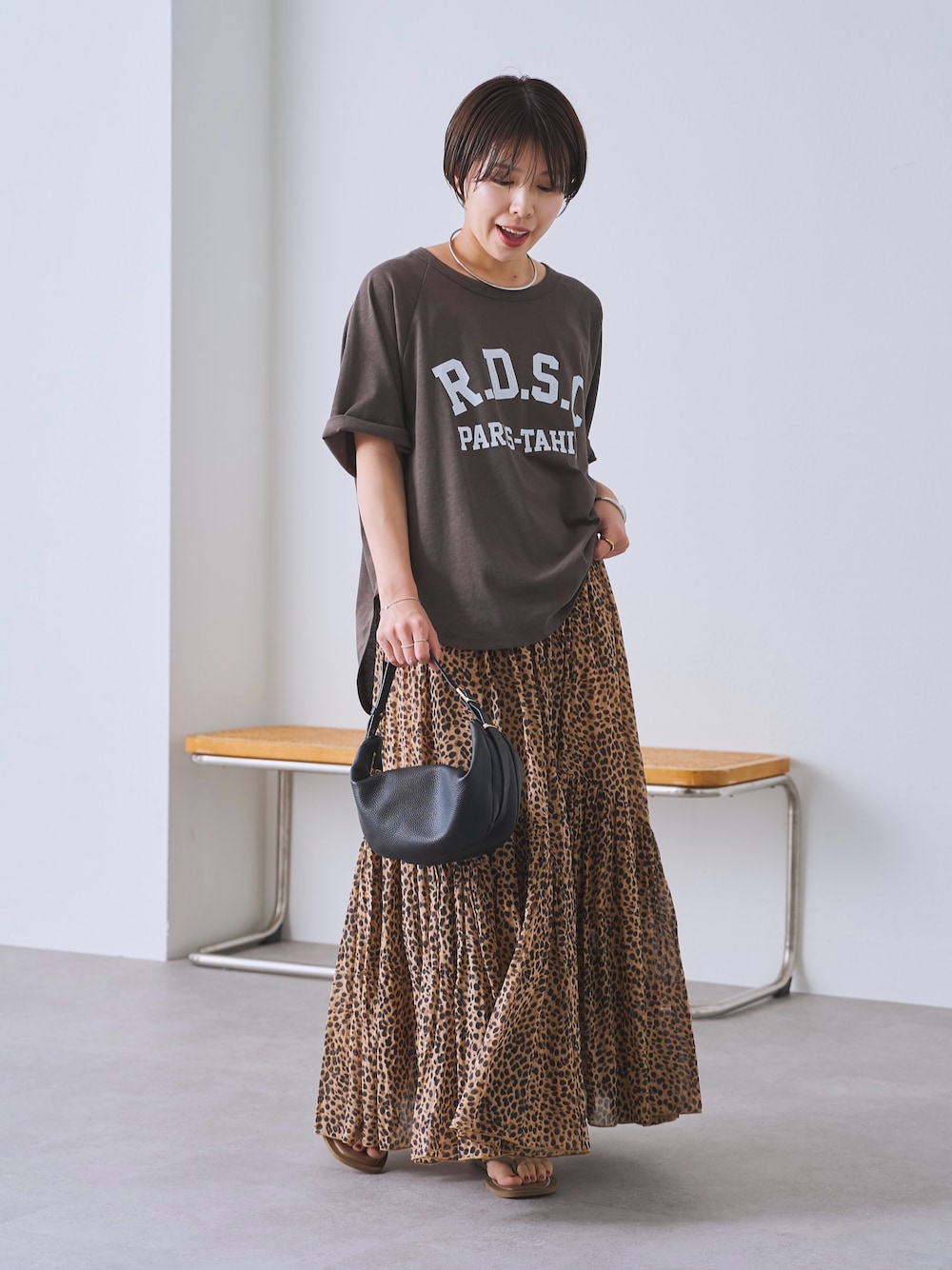 ベージュ系のスカート、ブラック系のショルダーバッグ、ブラウン系のTシャツ/カットソーを着用したレディースの春コーディネートの1枚目の写真