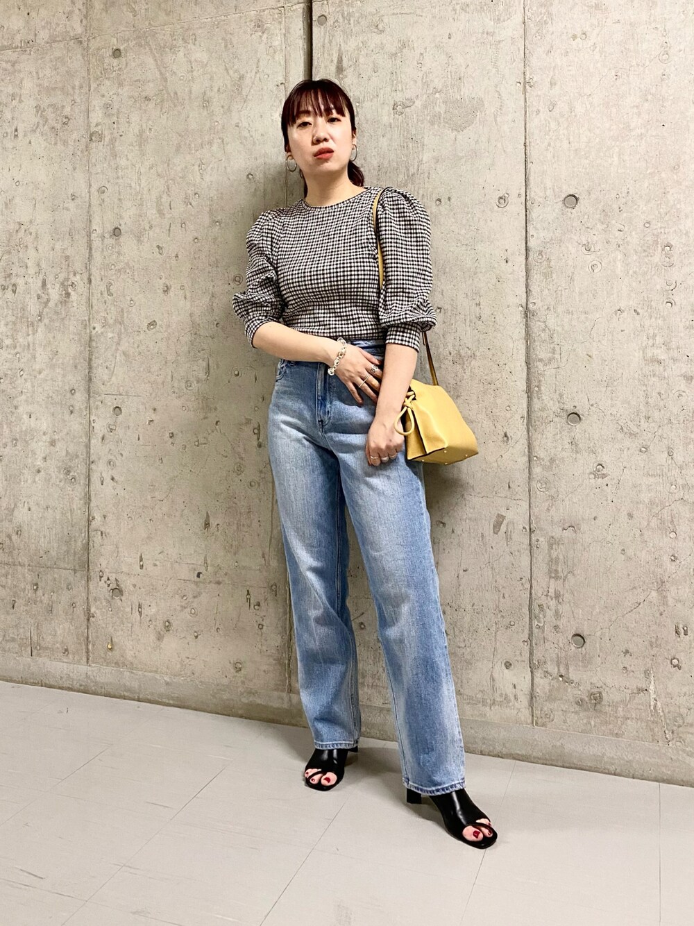ブルー系のデニムパンツ、ブラック系のサンダル、ベージュ系のショルダーバッグを着用したレディースの春コーディネートの1枚目の写真