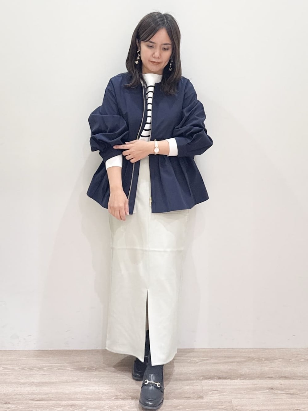 ブラック系のパンプス、パープル系のショルダーバッグ、ベージュ系のスカートを着用したレディースの春コーディネートの1枚目の写真