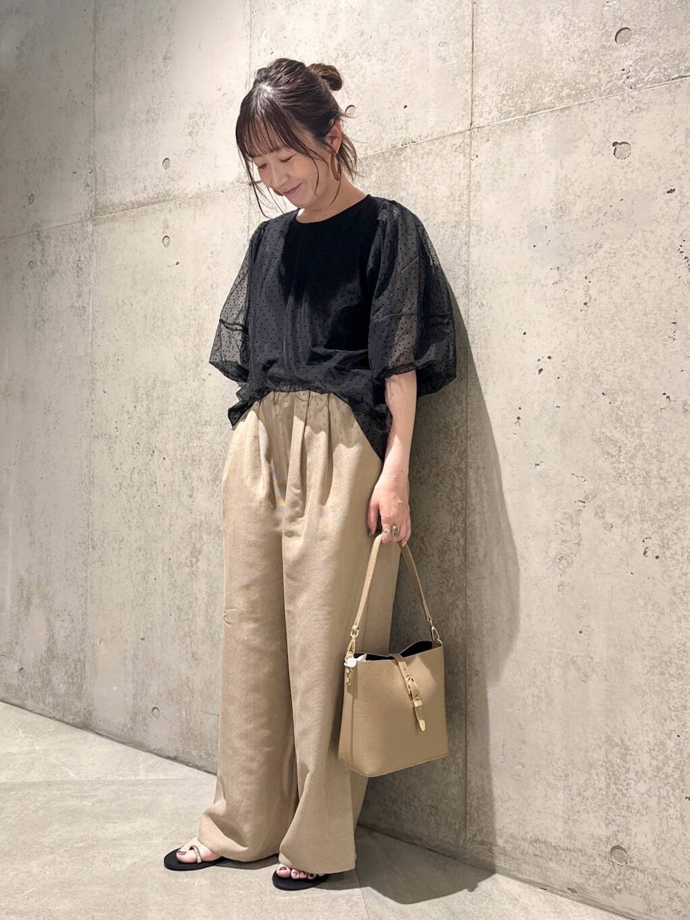 ベージュ系のショルダーバッグ、ブラック系のサンダル、ブラック系のTシャツ/カットソーを着用したレディースの夏コーディネートの1枚目の写真