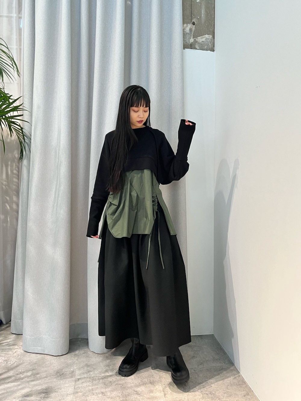 ベージュ系のキャミソール、ブラック系のスカート、ブラック系のブーツを着用したレディースの冬コーディネートの1枚目の写真