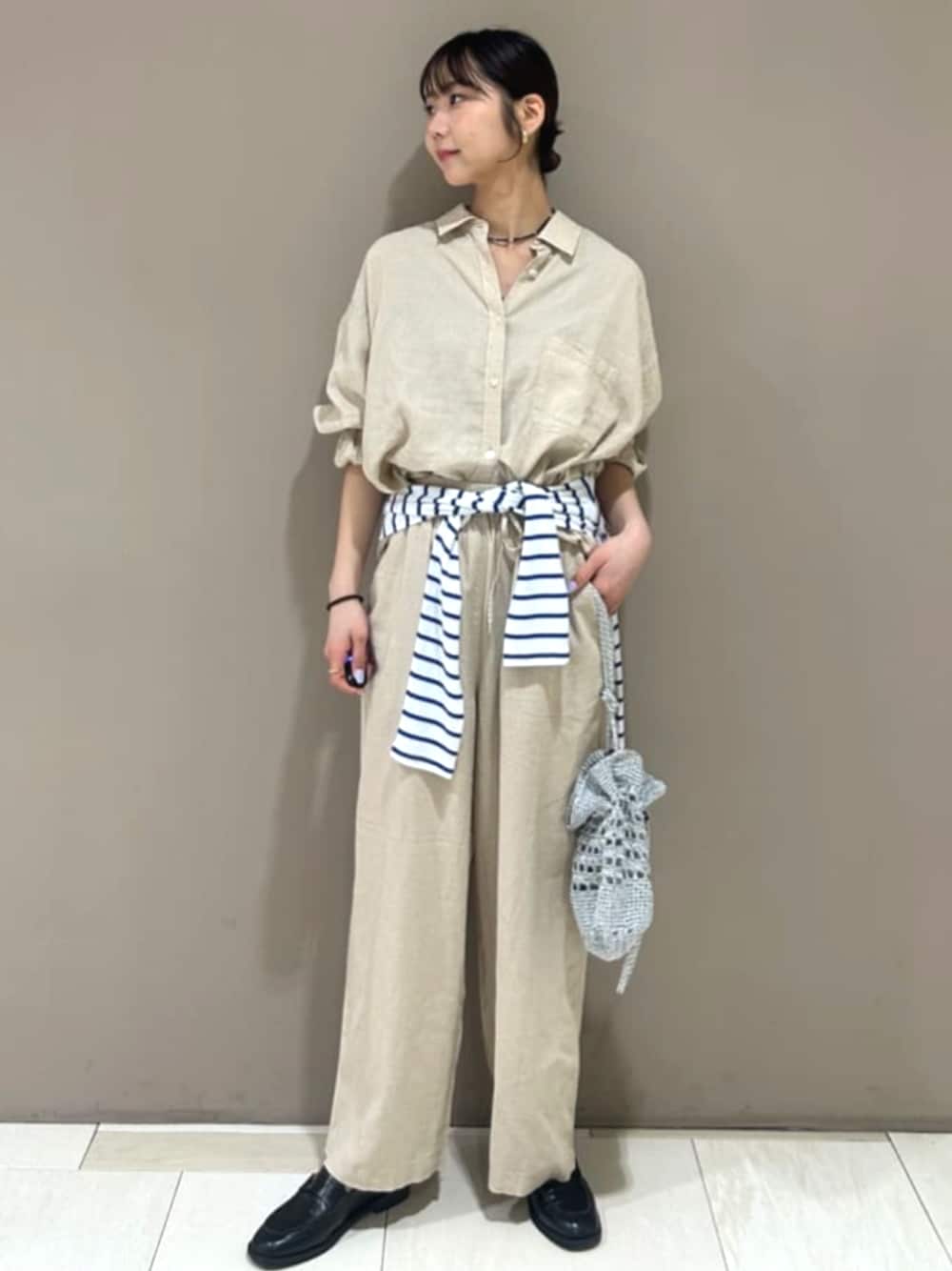 シルバー系のショルダーバッグ、ベージュ系のスラックス、ベージュ系のシャツ/ブラウスを着用したレディースの春コーディネートの1枚目の写真