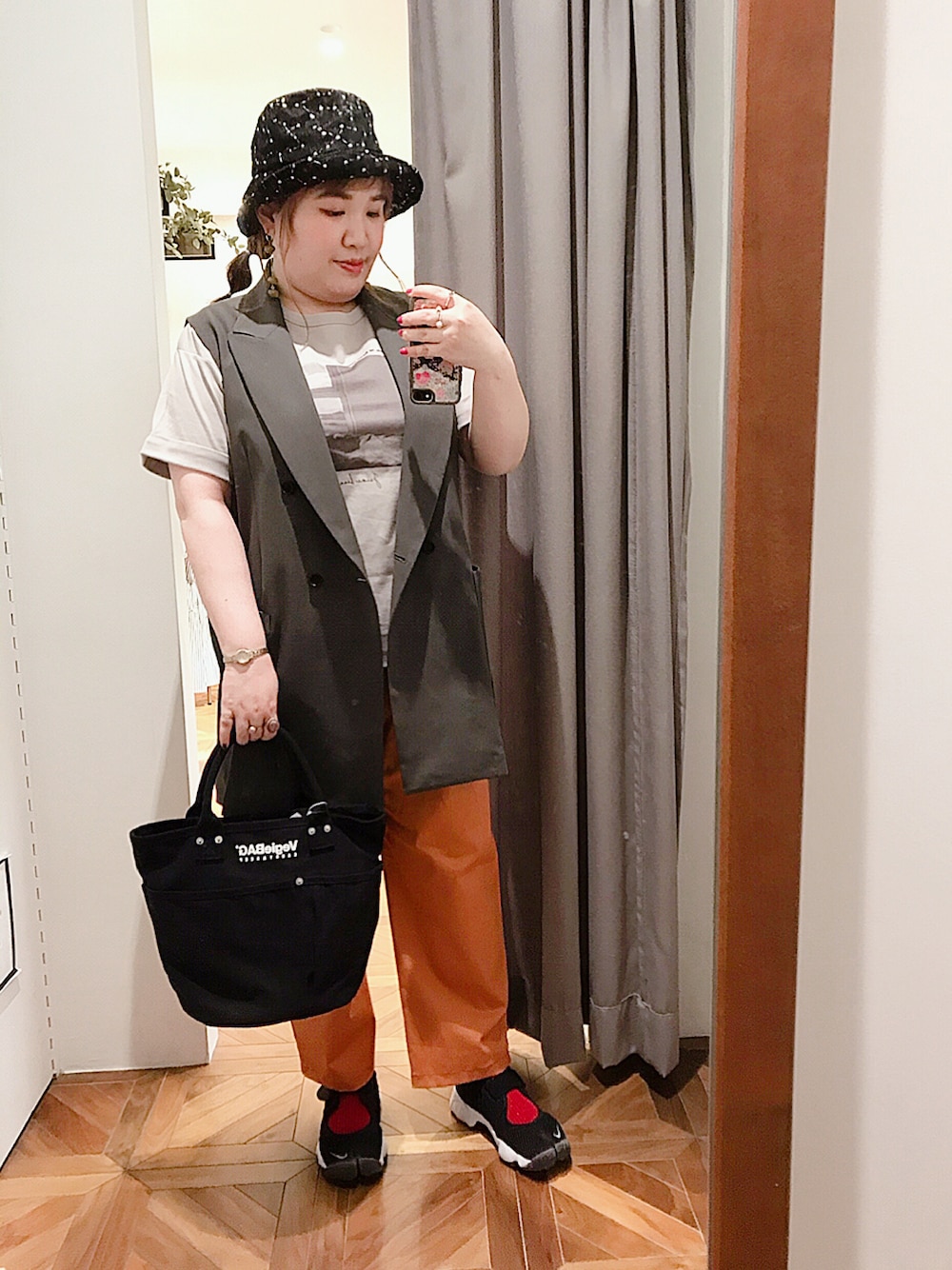 グレー系のベスト、ベージュ系のTシャツ/カットソー、オレンジ系のその他パンツを着用したレディースの春コーディネートの1枚目の写真
