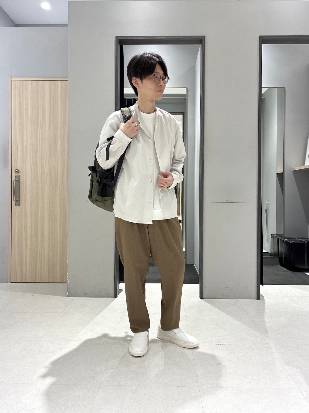 グリーン系のバックパック/リュック、ホワイト系のTシャツ/カットソー、ブラック系のニット/セーターを着用したメンズの春コーディネートの1枚目の写真
