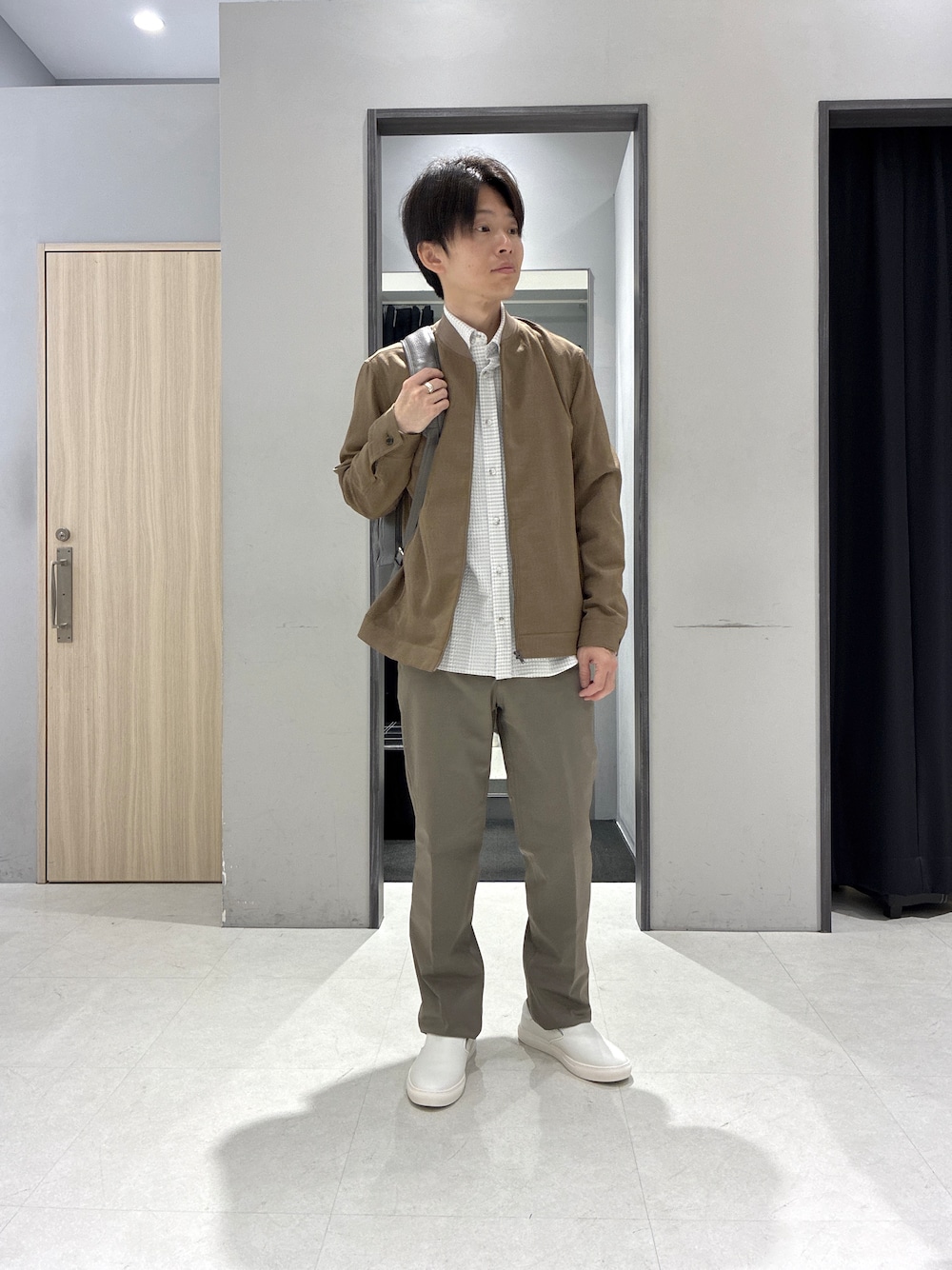 グレー系のシャツ/ブラウス、グレー系のバックパック/リュック、ホワイト系のポロシャツを着用したメンズの春コーディネートの1枚目の写真