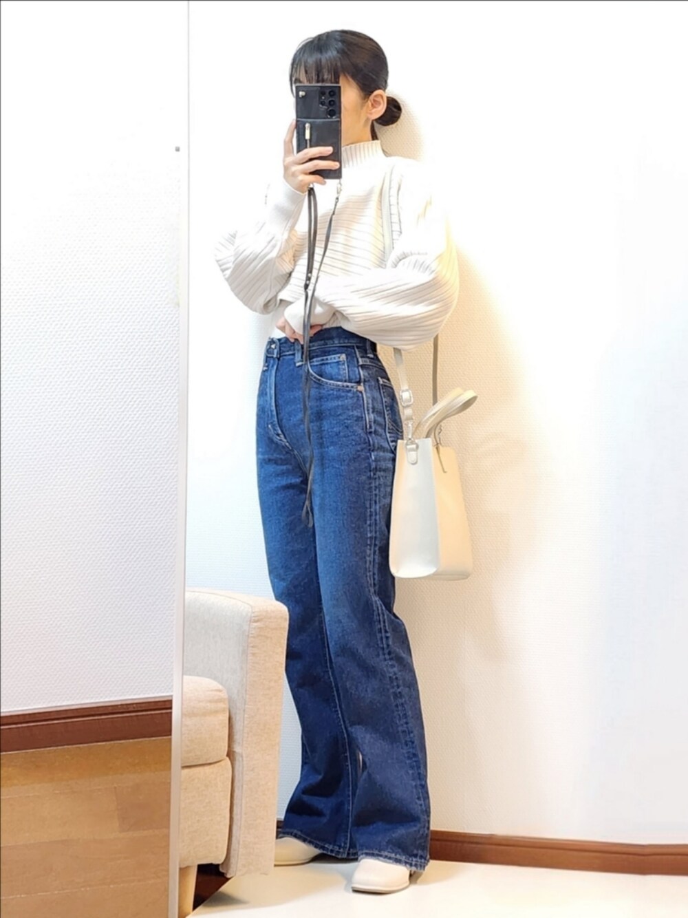ホワイト系のアンサンブル、ブルー系のデニムパンツ、ベージュ系のショルダーバッグを着用したレディースの冬コーディネートの1枚目の写真