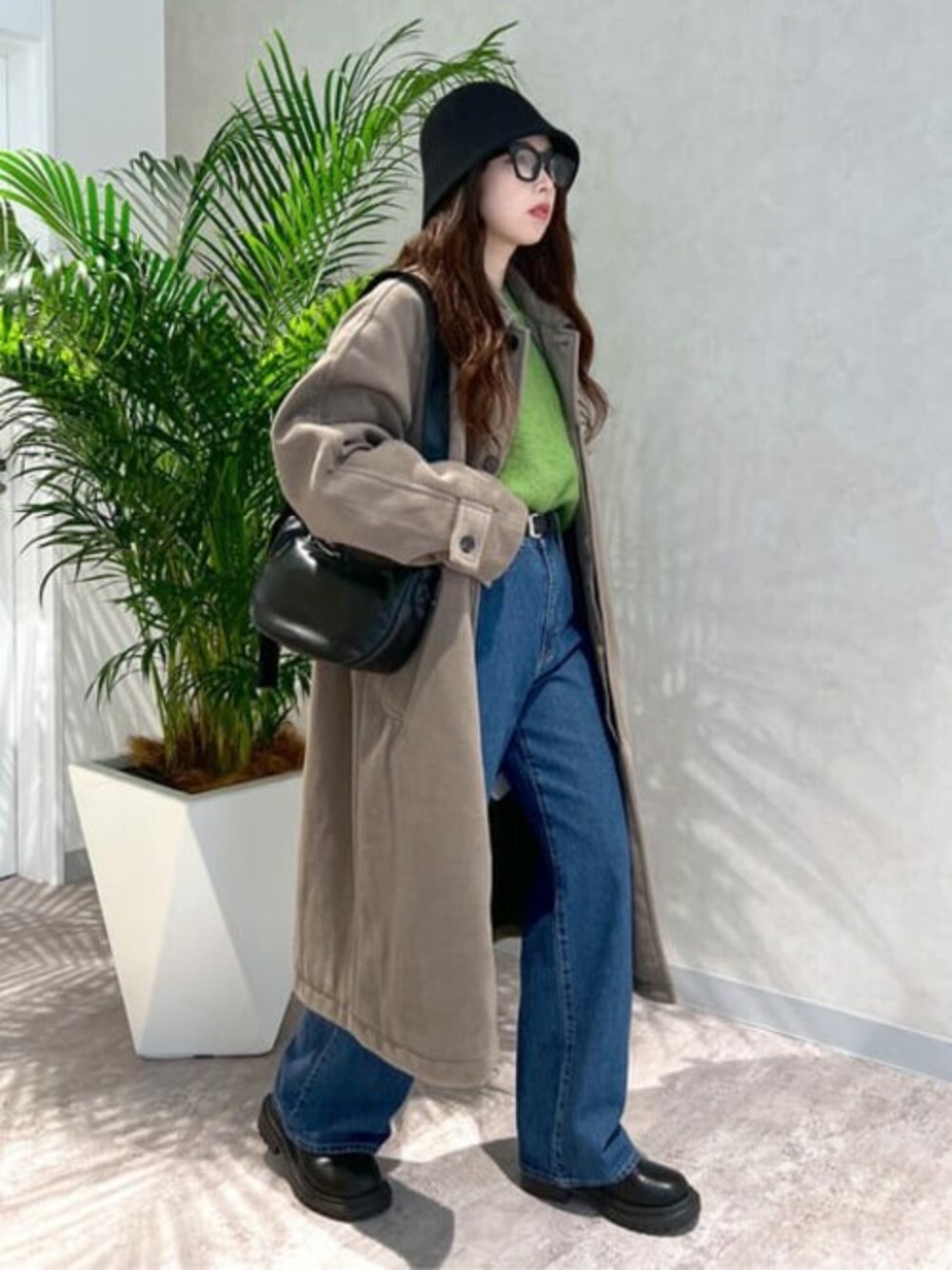 グリーン系のニット/セーター、ブルー系のデニムパンツ、ブラック系のブーツを着用したレディースの冬コーディネートの1枚目の写真
