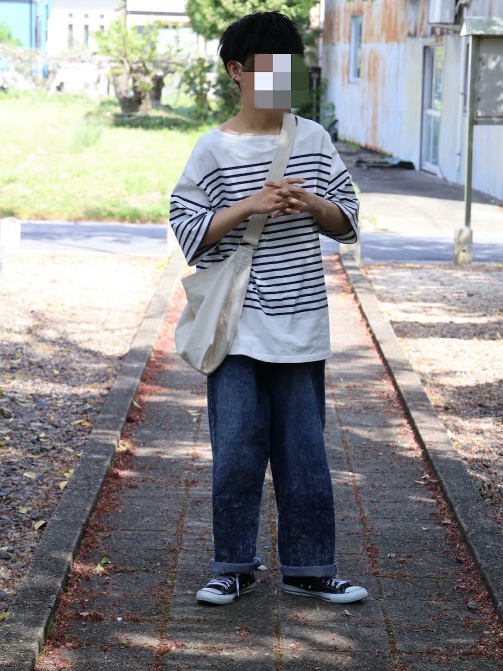 ブルー系のデニムパンツ、ブラック系のスニーカー、ホワイト系のショルダーバッグを着用したメンズの春コーディネートの1枚目の写真
