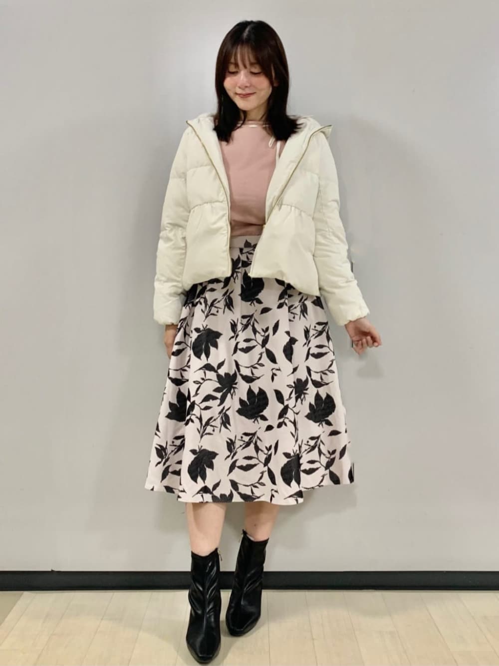 ピンク系のニット/セーター、ベージュ系のスカート、ベージュ系のダウンジャケット/コートを着用したレディースの秋コーディネートの1枚目の写真